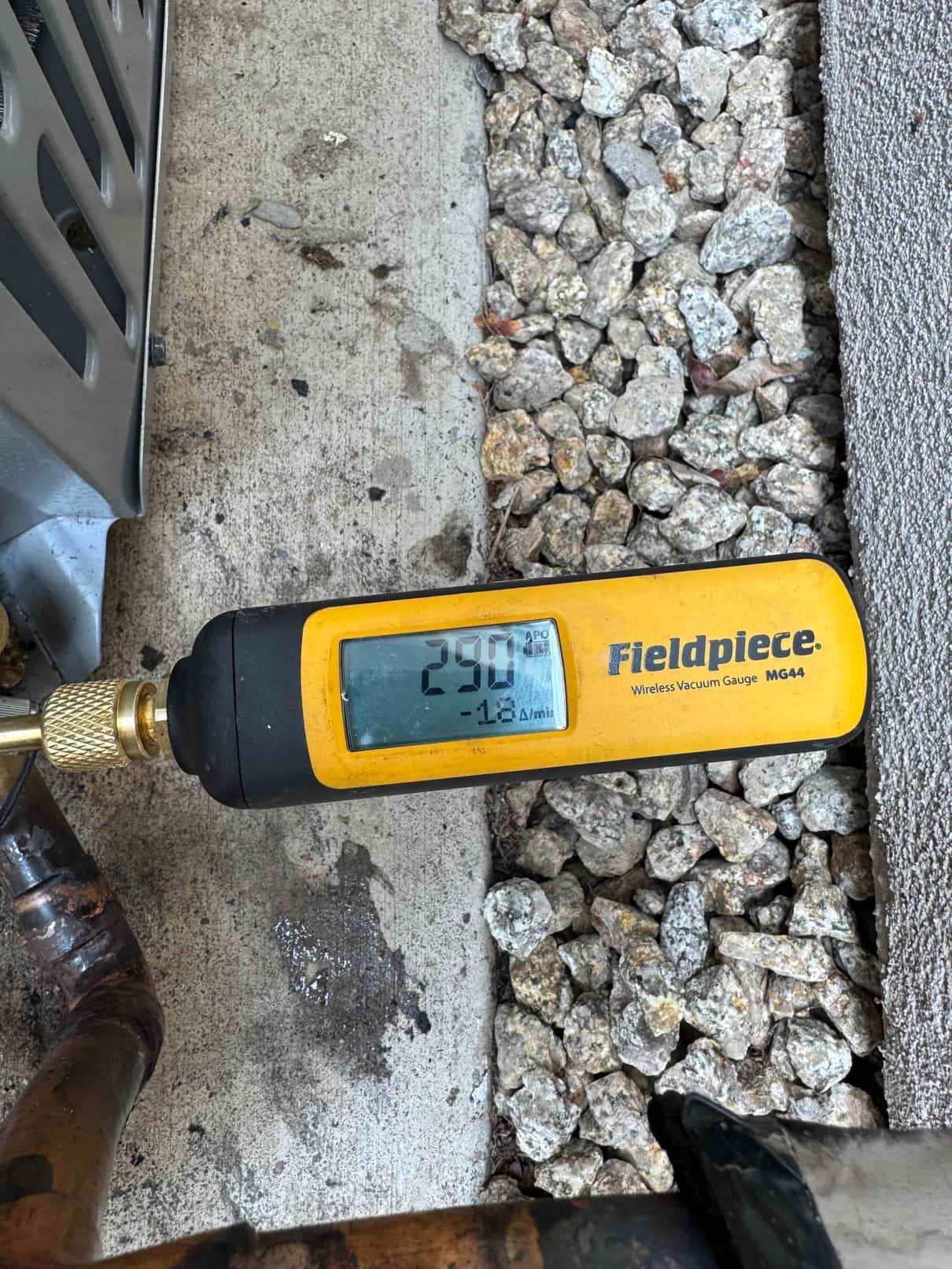 Wireless vacuum gauge connected to the HVAC system shows 290 microns, confirming a deep evacuation before refrigerant charging.