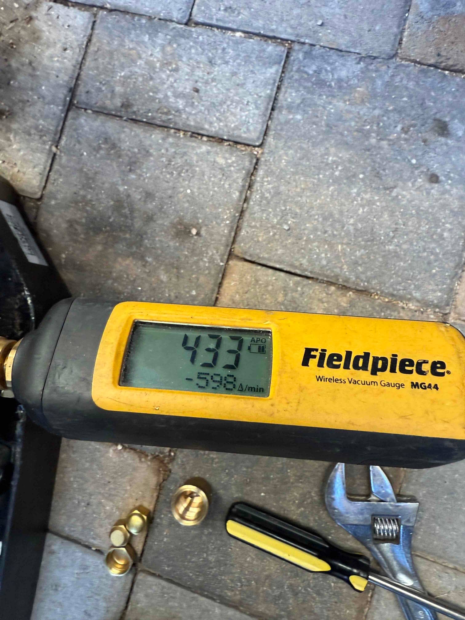 Wireless vacuum gauge shows 433 microns during system evacuation, confirming a deep vacuum before releasing refrigerant.