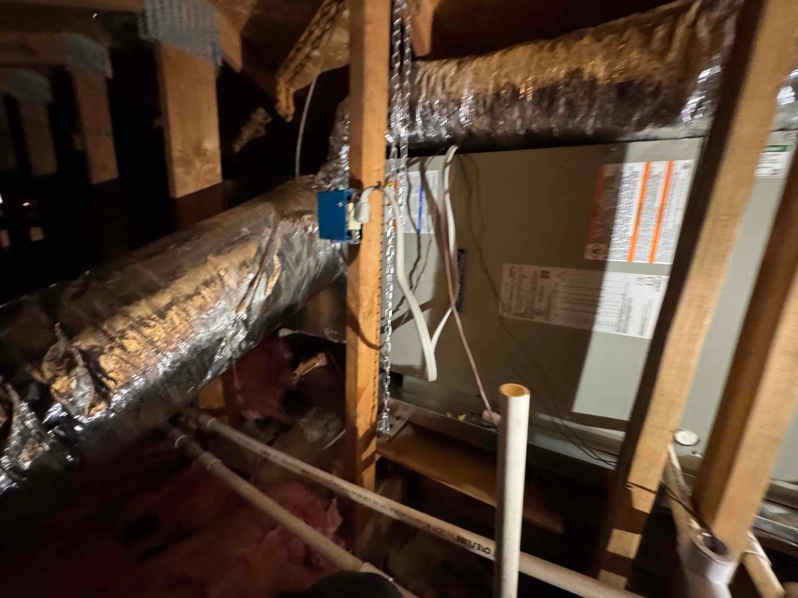 Air handler installed in attic with insulated duct connections, PVC condensate drain piping, and electrical whip routed to the unit.