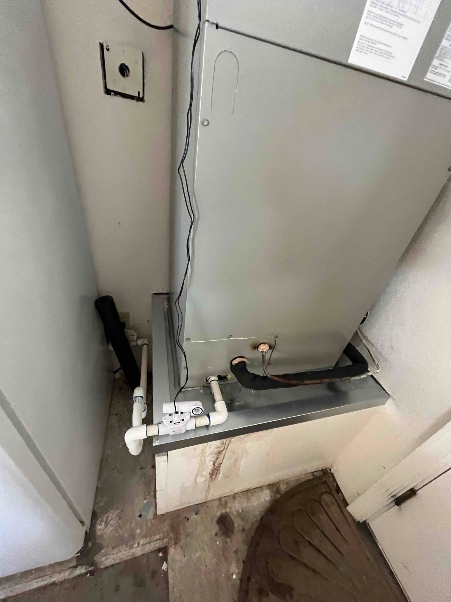 Air handler installed on a drain pan with insulated refrigerant line, condensate trap, float switch, and PVC drain routing.