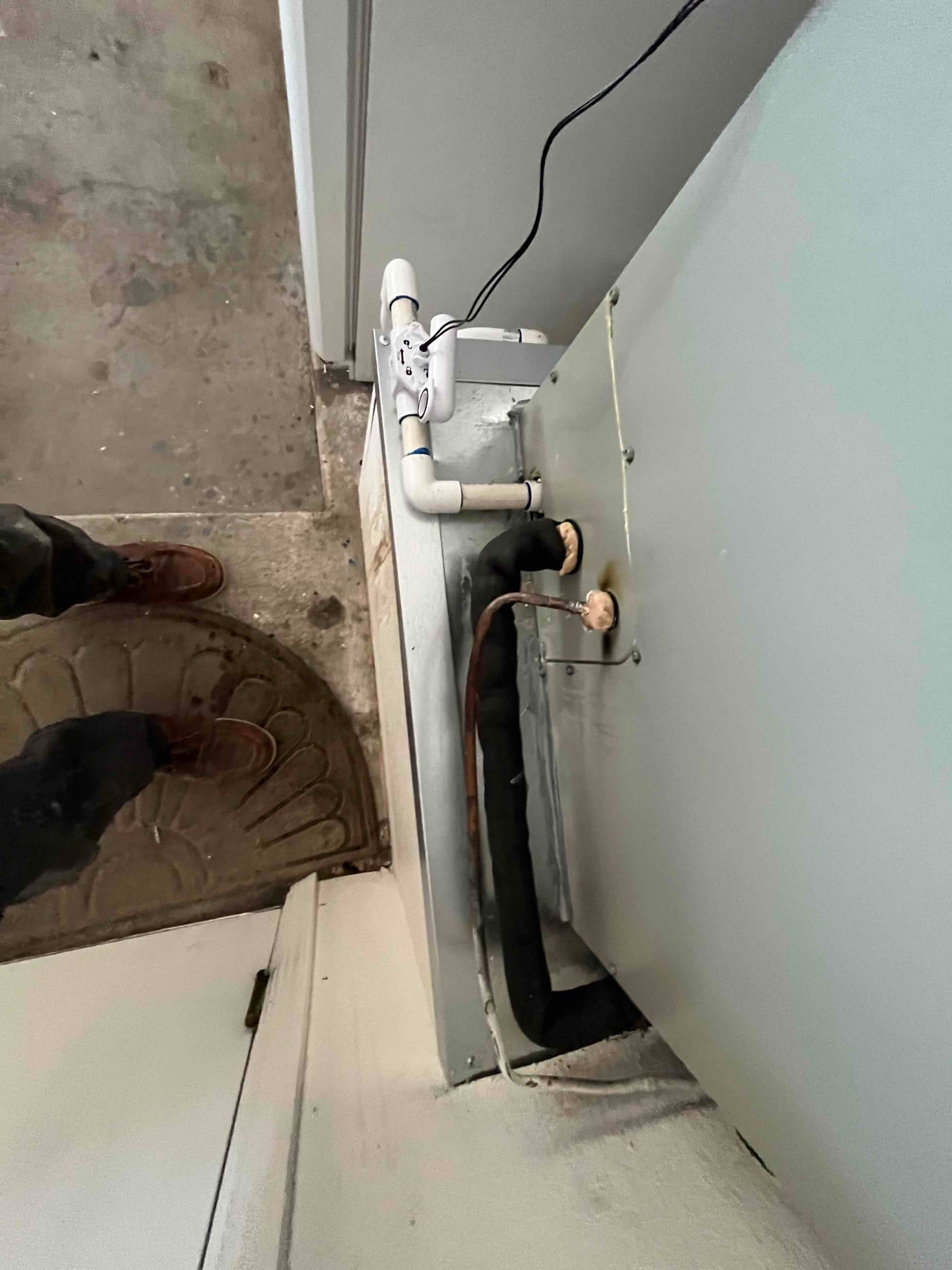 Air handler installed with insulated refrigerant line set, condensate drain with float switch, and sealed cabinet connections.