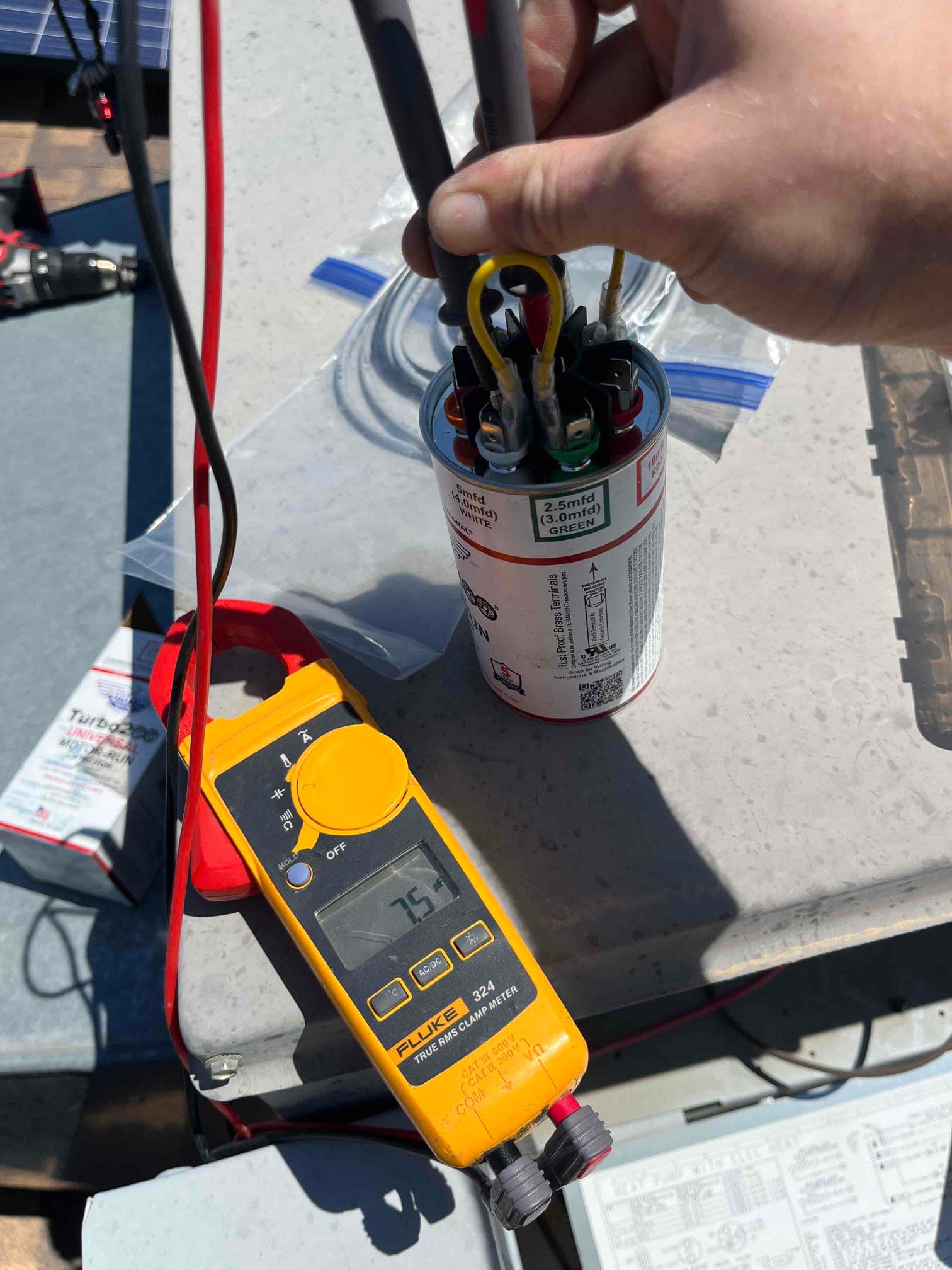 Capacitance meter reads 15.7 μF while testing the terminals of a dual run capacitor during air conditioning repair.