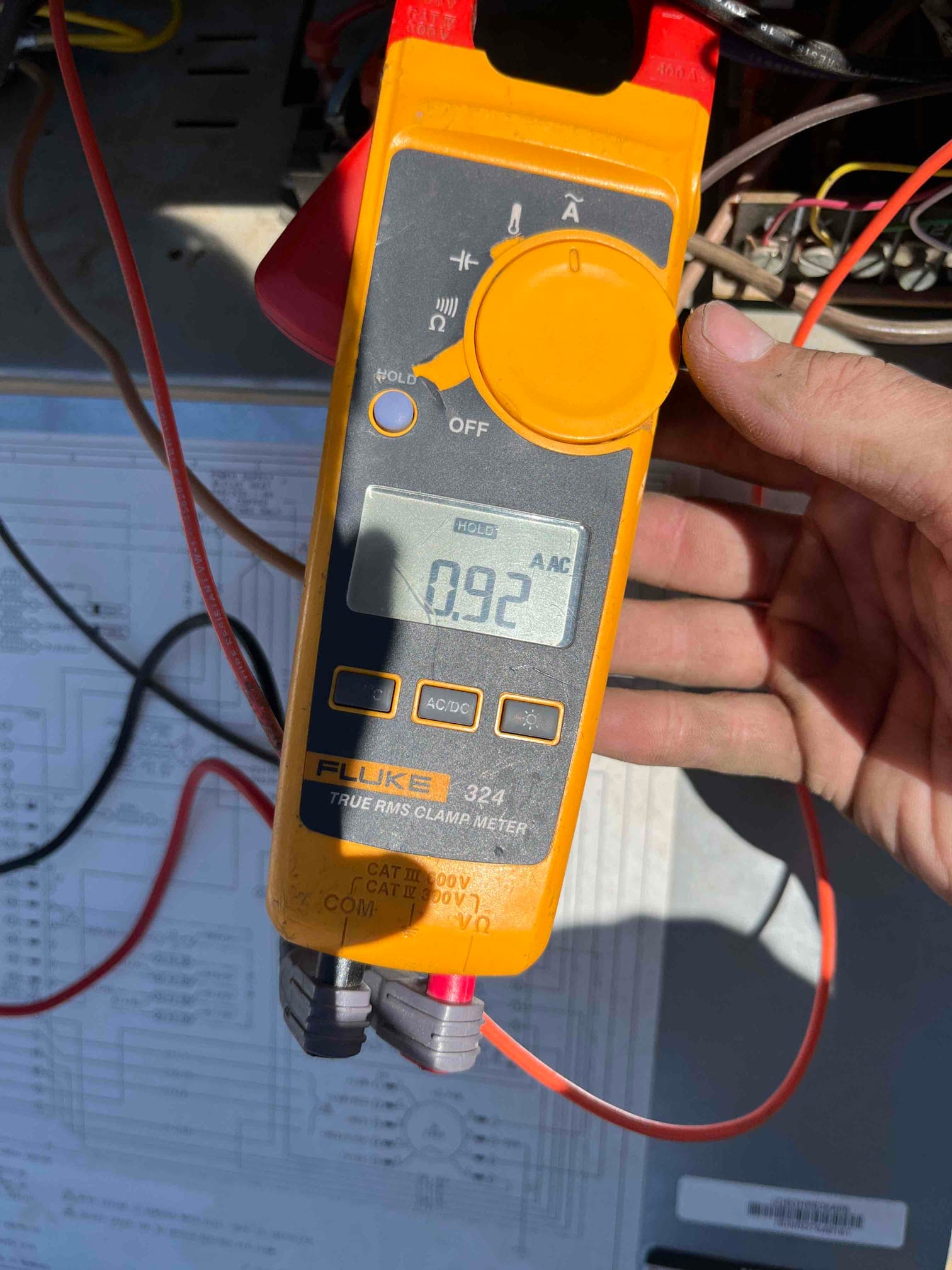 Clamp meter displays 0.92 A AC while measuring current on a single conductor at the outdoor condenser.