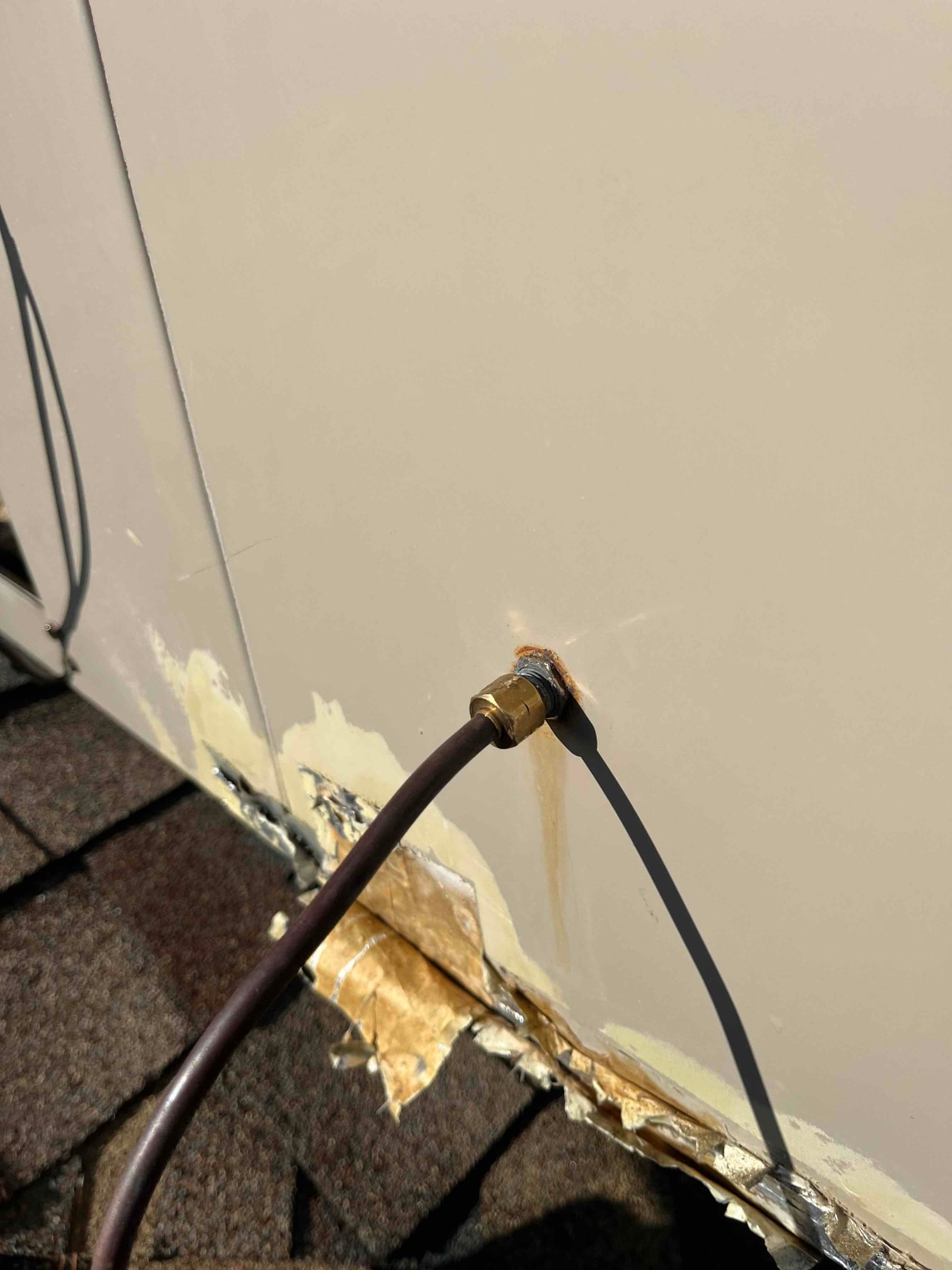Copper refrigerant or drain line penetrates an exterior panel with a brass bulkhead fitting and visible rust staining at the entry.