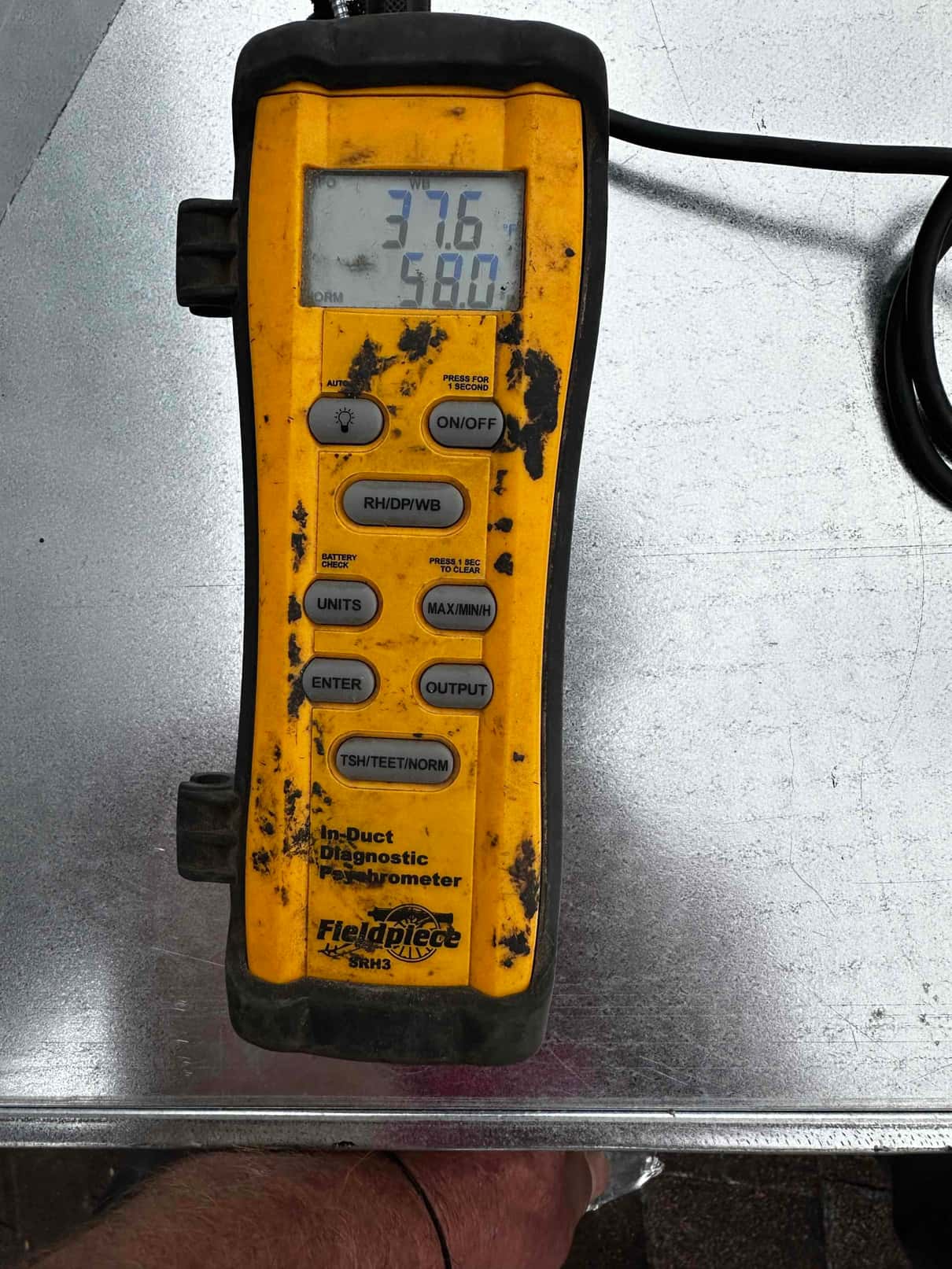 Digital in-duct thermometer shows 58.0 degrees Fahrenheit, documenting supply air temperature during system commissioning.