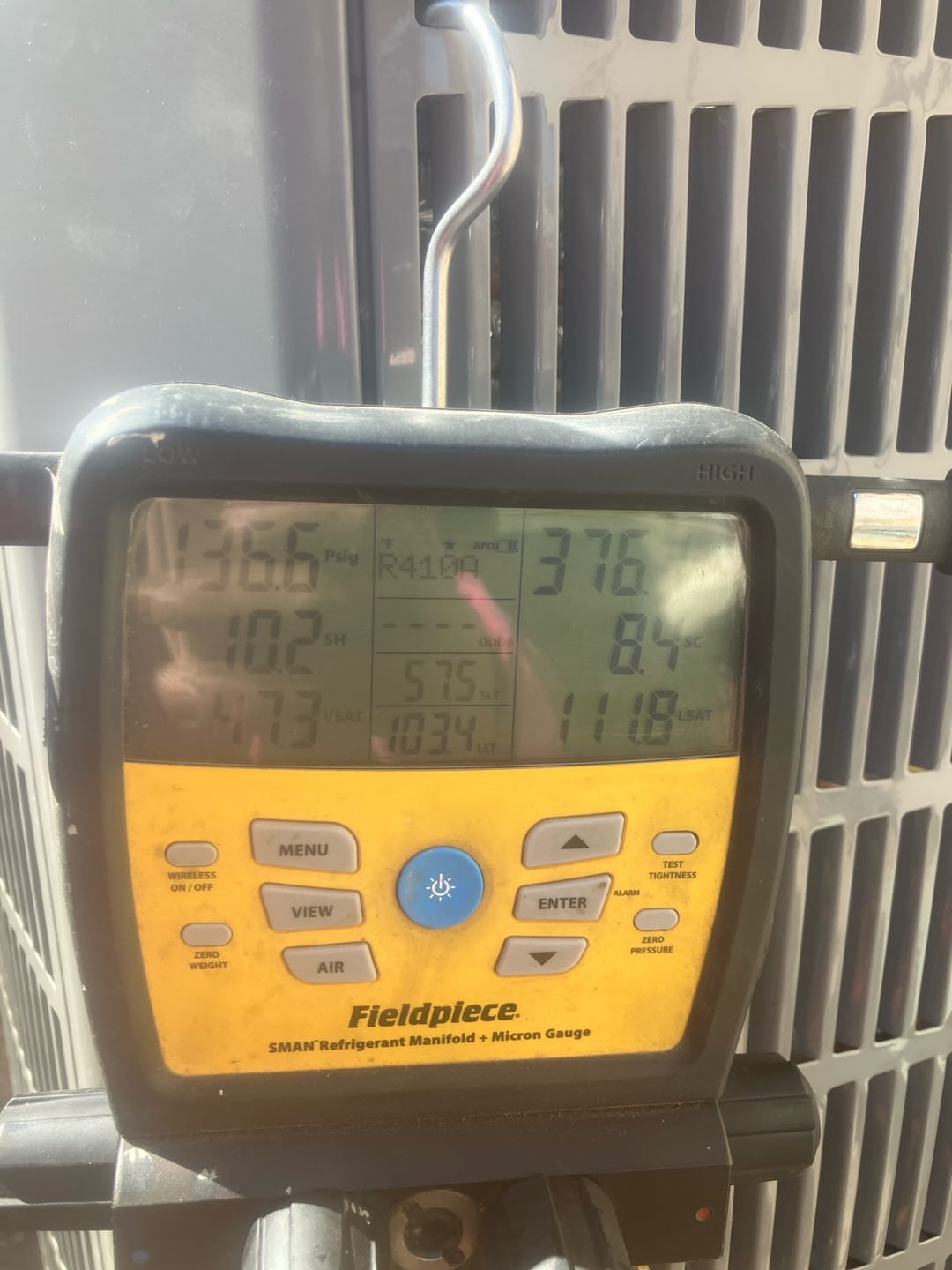 Digital manifold connected at the outdoor unit shows operating pressures with low and high sides displayed during system commissioning.