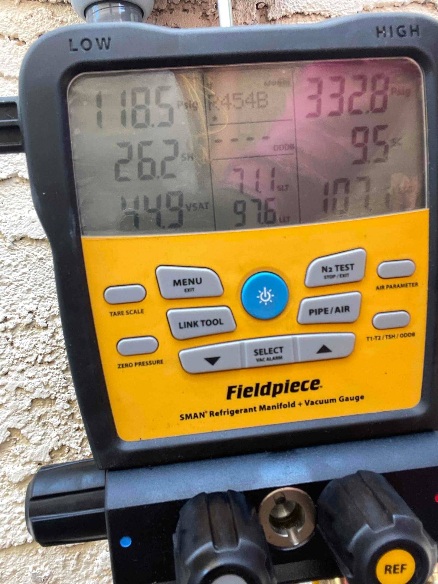 Digital manifold shows operating pressures of 118.5 PSI low side and 332.8 PSI high side while commissioning the system with R‑454B.
