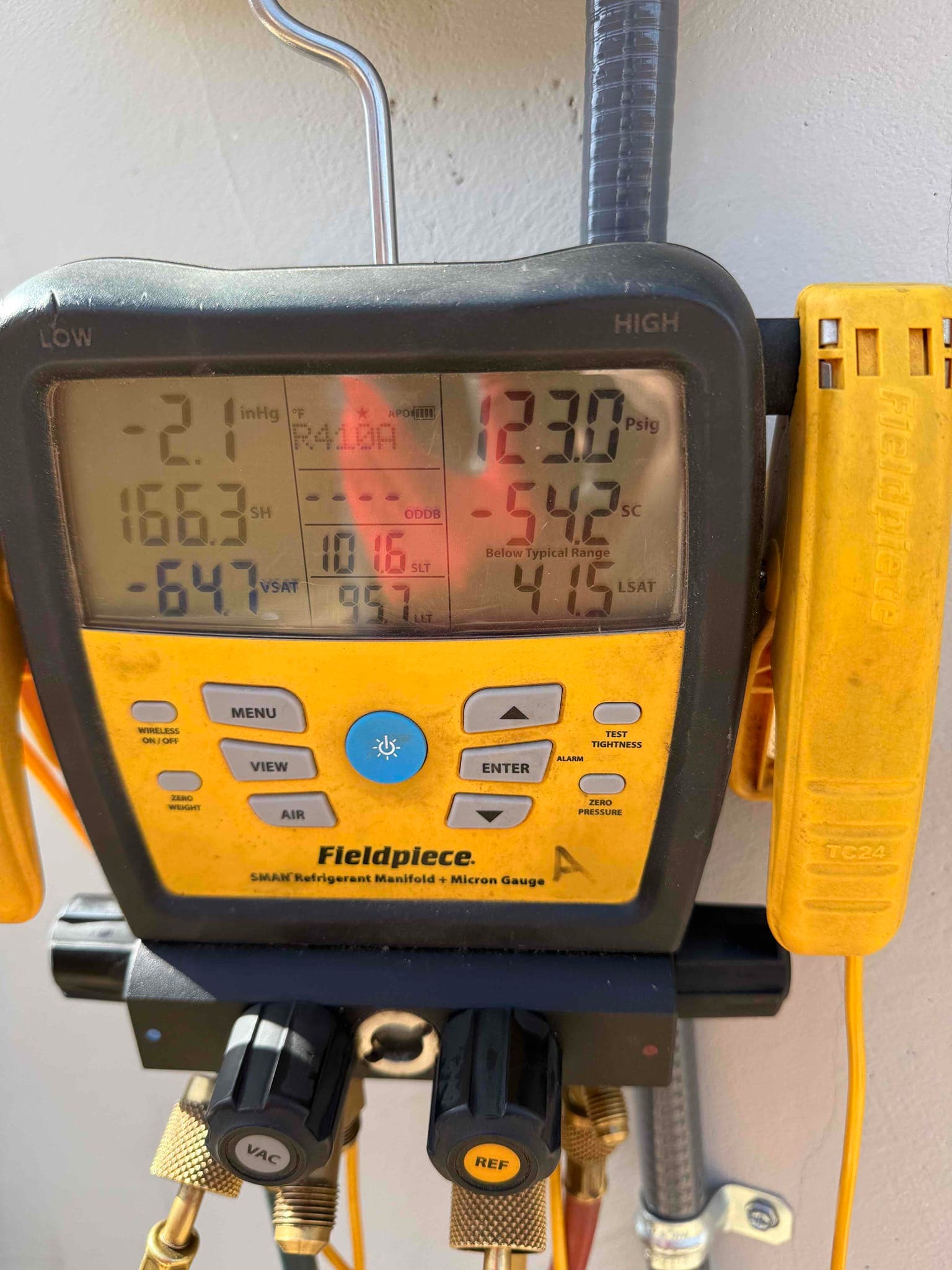 Digital manifold shows operating pressures with R‑410A selected, indicating the system is running during refrigerant commissioning checks.
