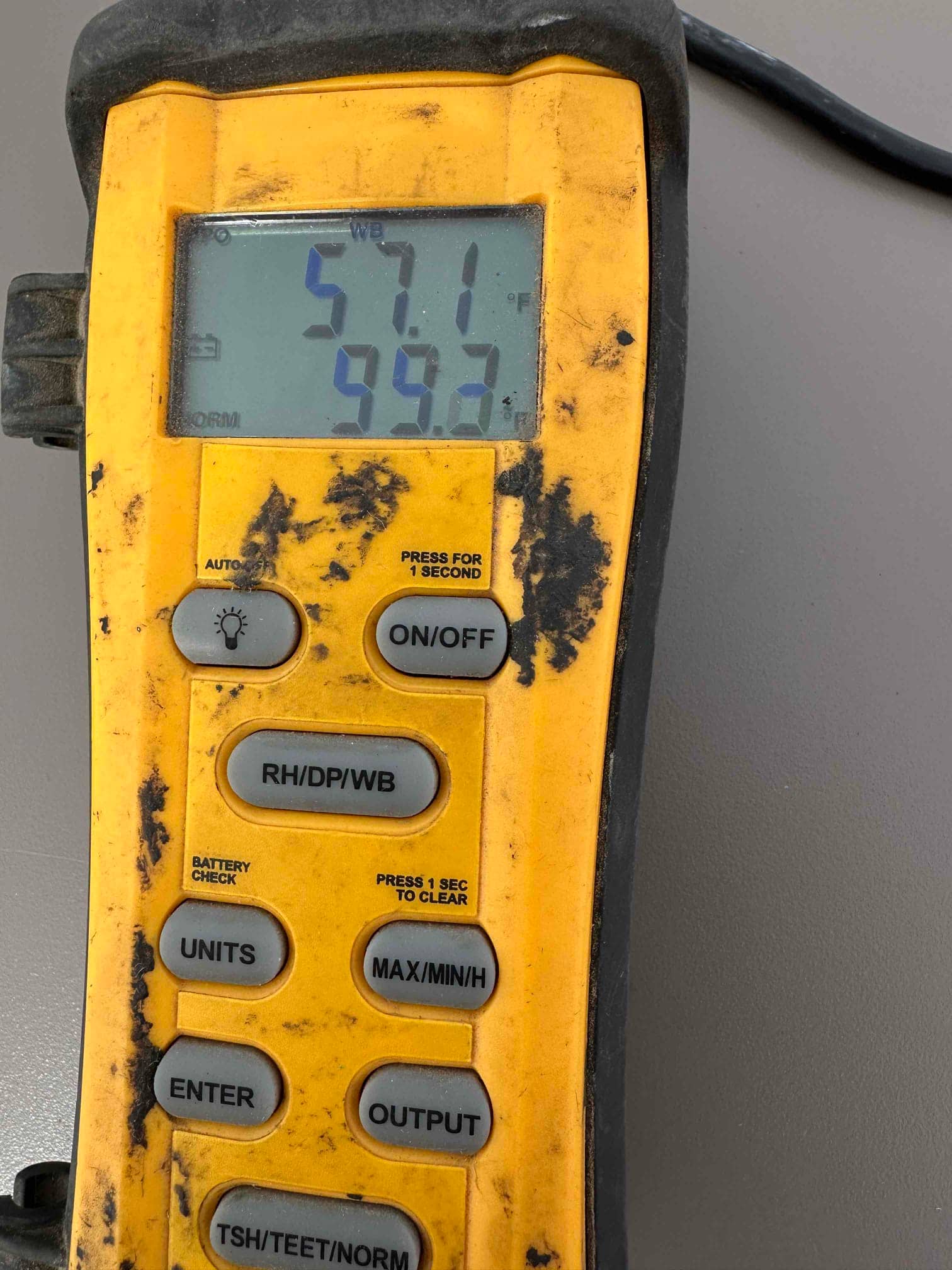 Digital thermometer displays 57.1°F on the upper readout and 59.2°F on the lower during air temperature measurement.