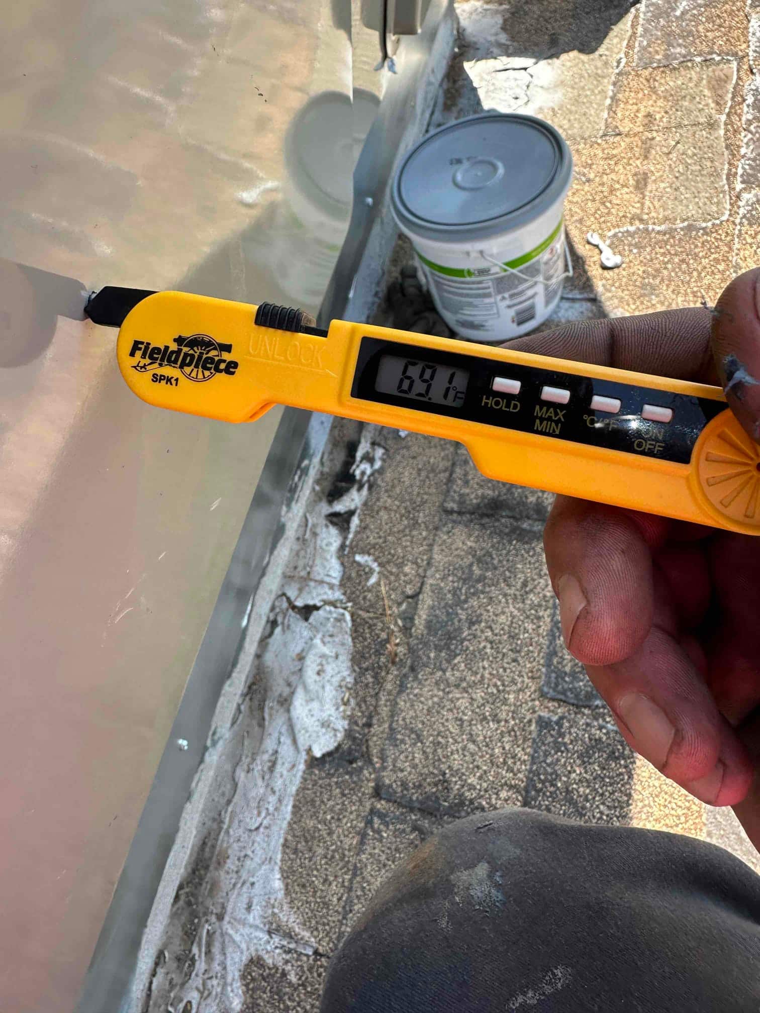Digital thermometer displays 69.1°F while measuring air temperature during commissioning of the installed HVAC system.