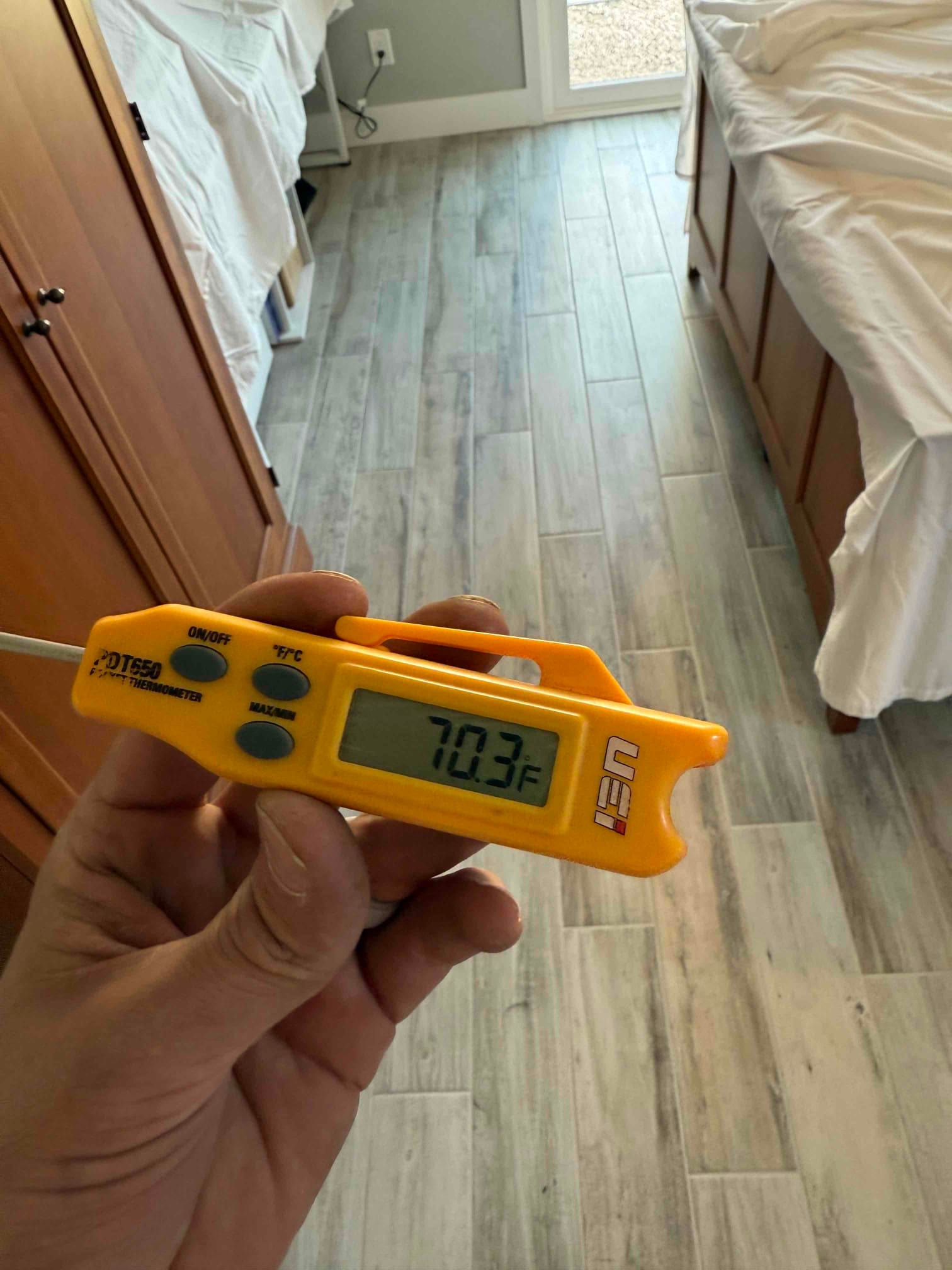 Digital thermometer displays 70.3°F while measuring indoor air temperature during HVAC commissioning checks.