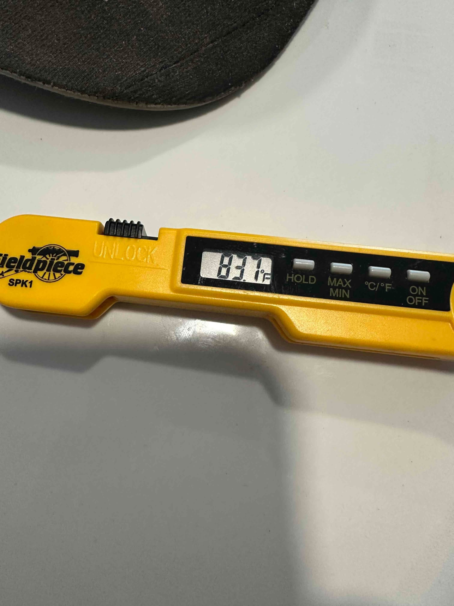 Digital thermometer displays 83°F during air temperature check, documenting return air conditions at the HVAC system.