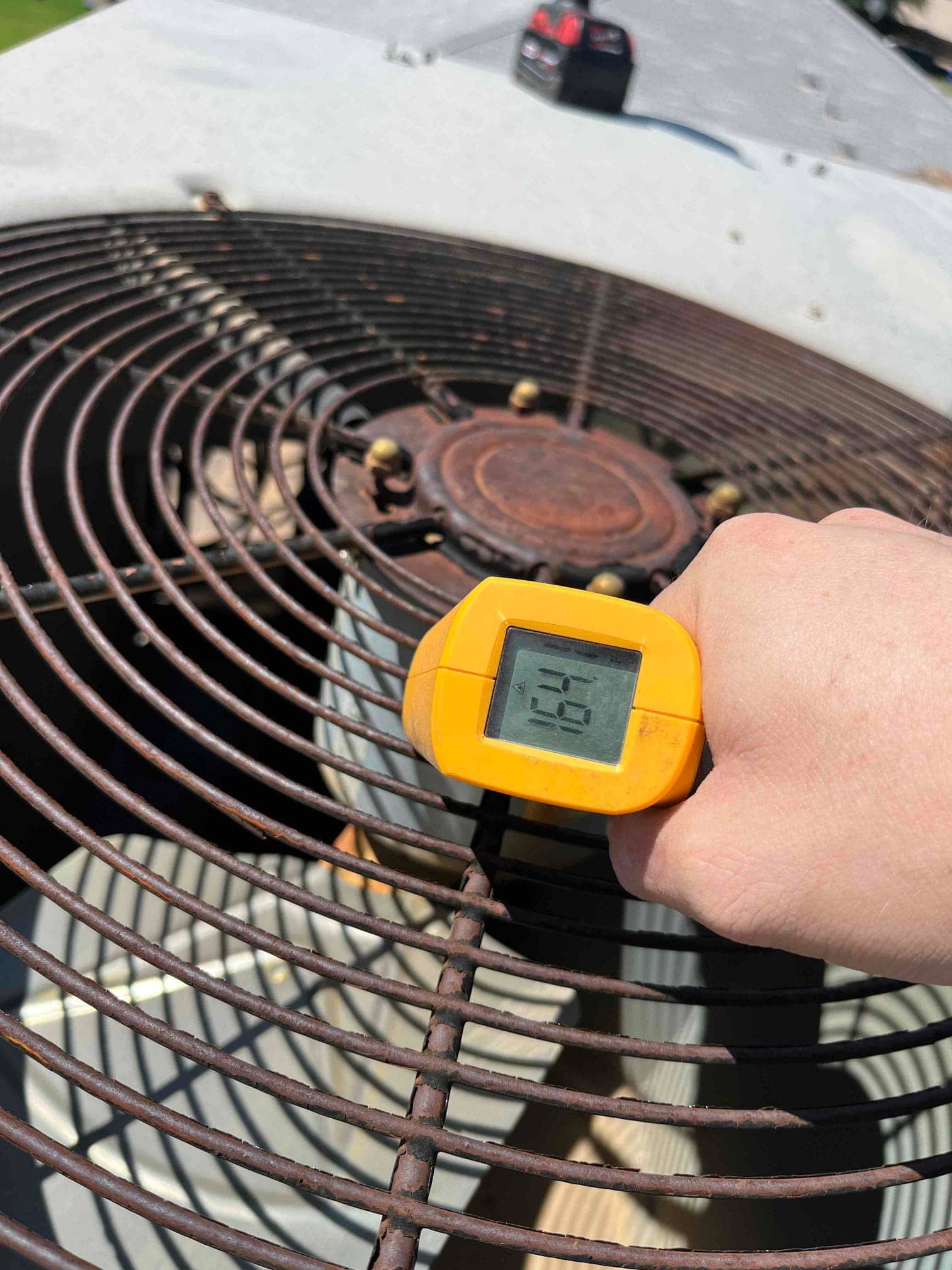 Digital thermometer reads 164 °F on the condenser fan motor housing through the top grille during operation.