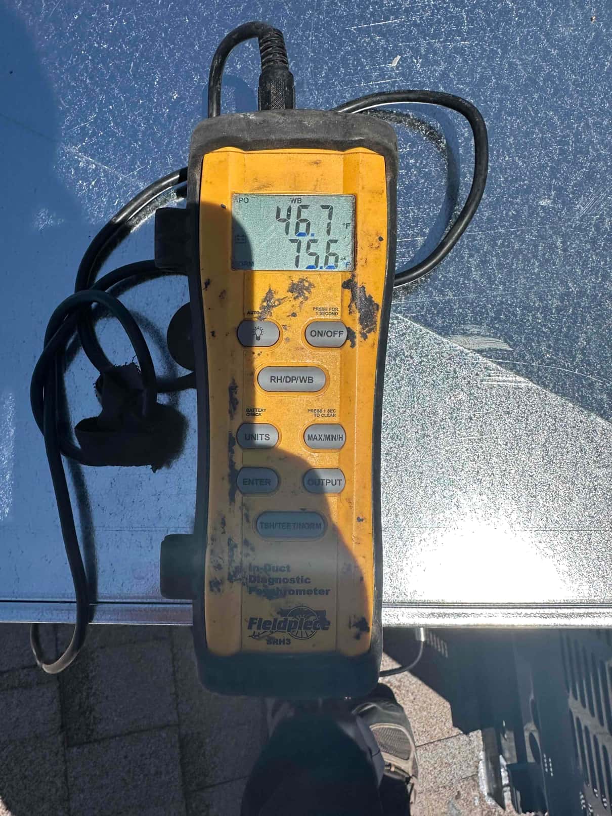 Digital thermometer shows 46.7°F supply air and 75.6°F return air during air-side commissioning on the new installation.