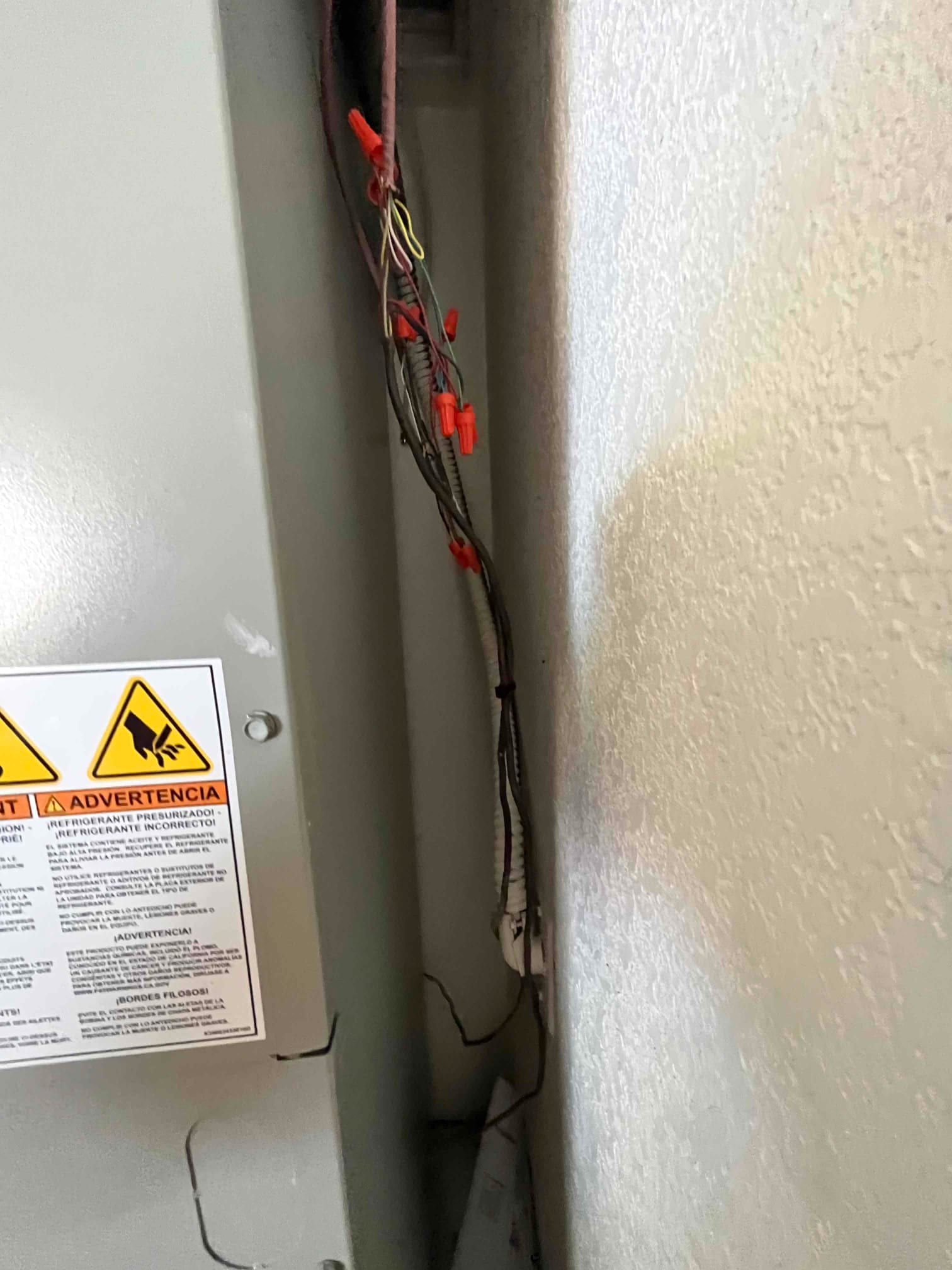 Low-voltage control wiring with multiple wire nuts routed alongside the air handler cabinet during installation.