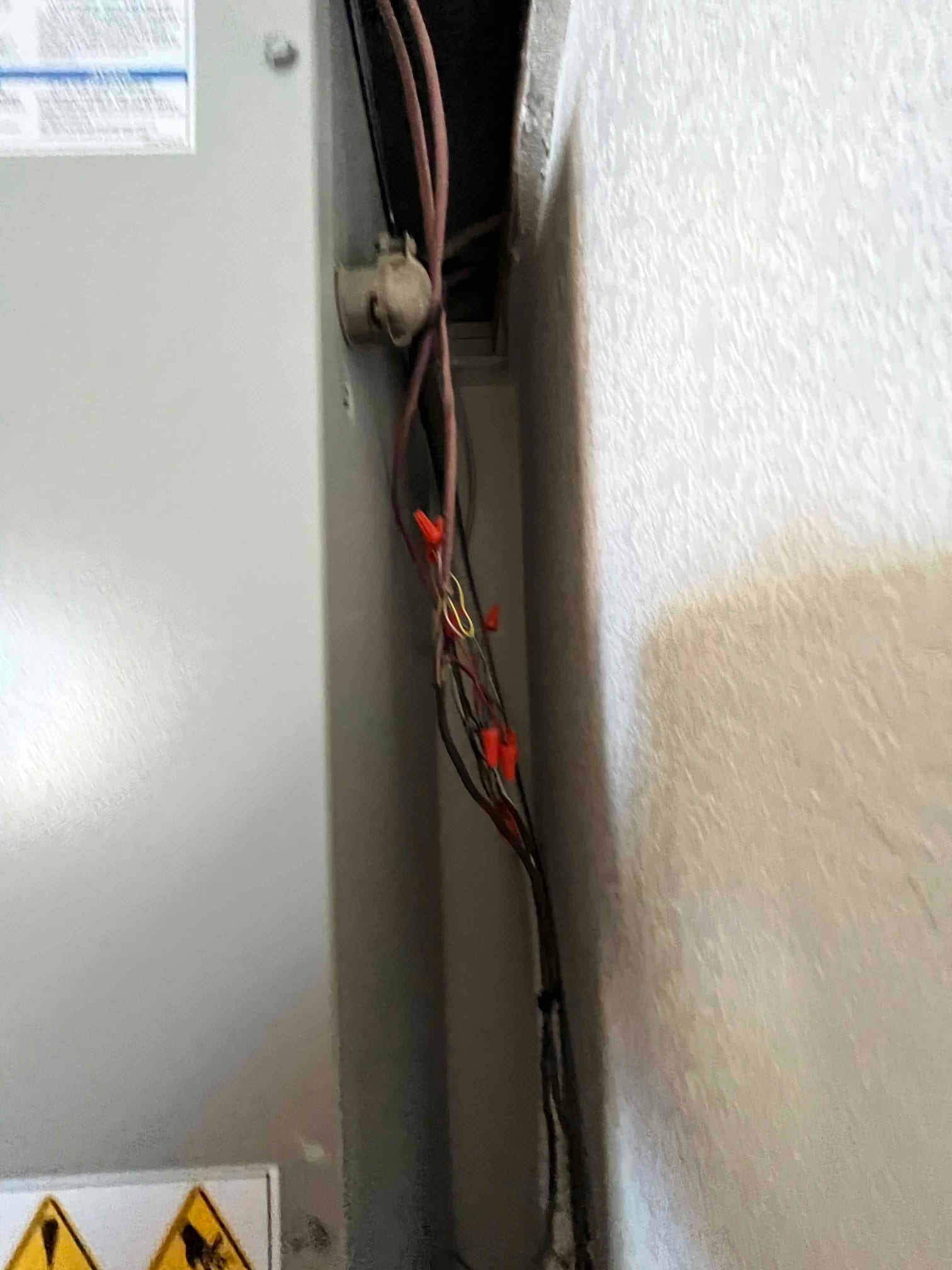Low-voltage thermostat wiring with wire connectors routed along the side of an indoor air handler cabinet.