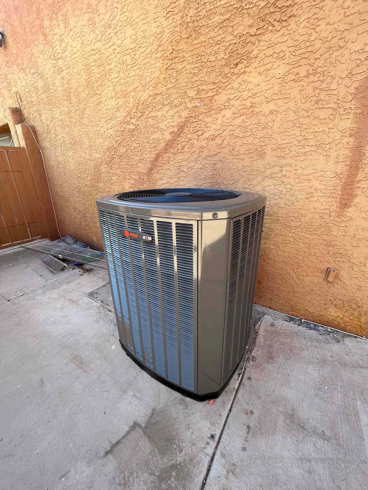 New outdoor heat pump condenser set on a level pad beside the exterior wall with clear service clearance.