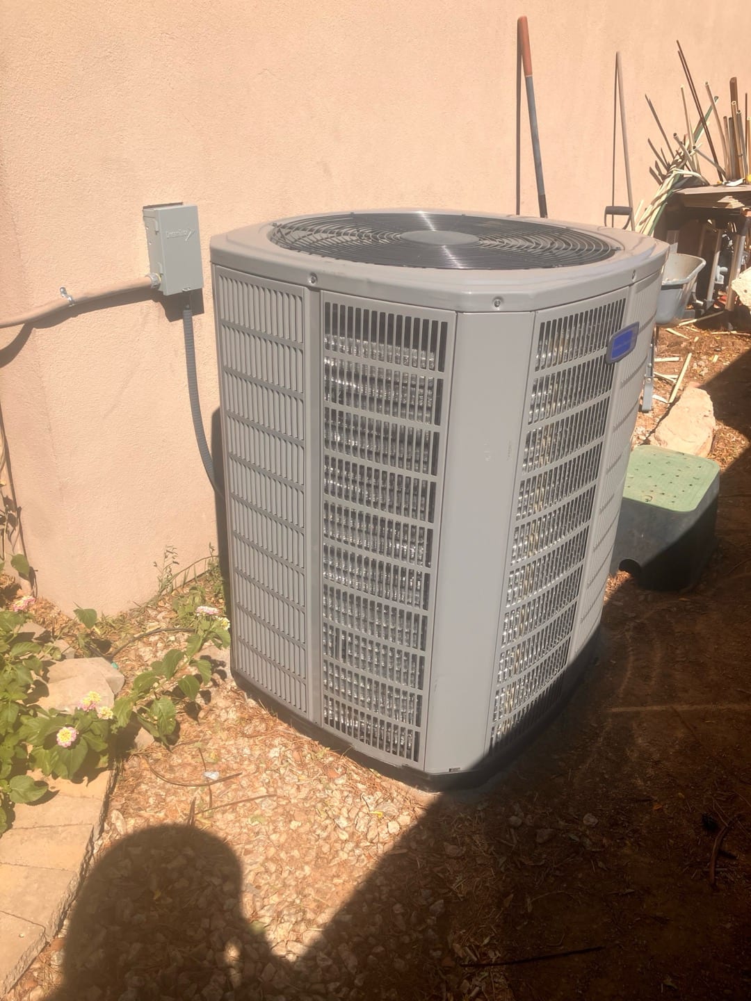 New outdoor heat pump condenser set on a level pad with nearby disconnect box and insulated electrical whip.