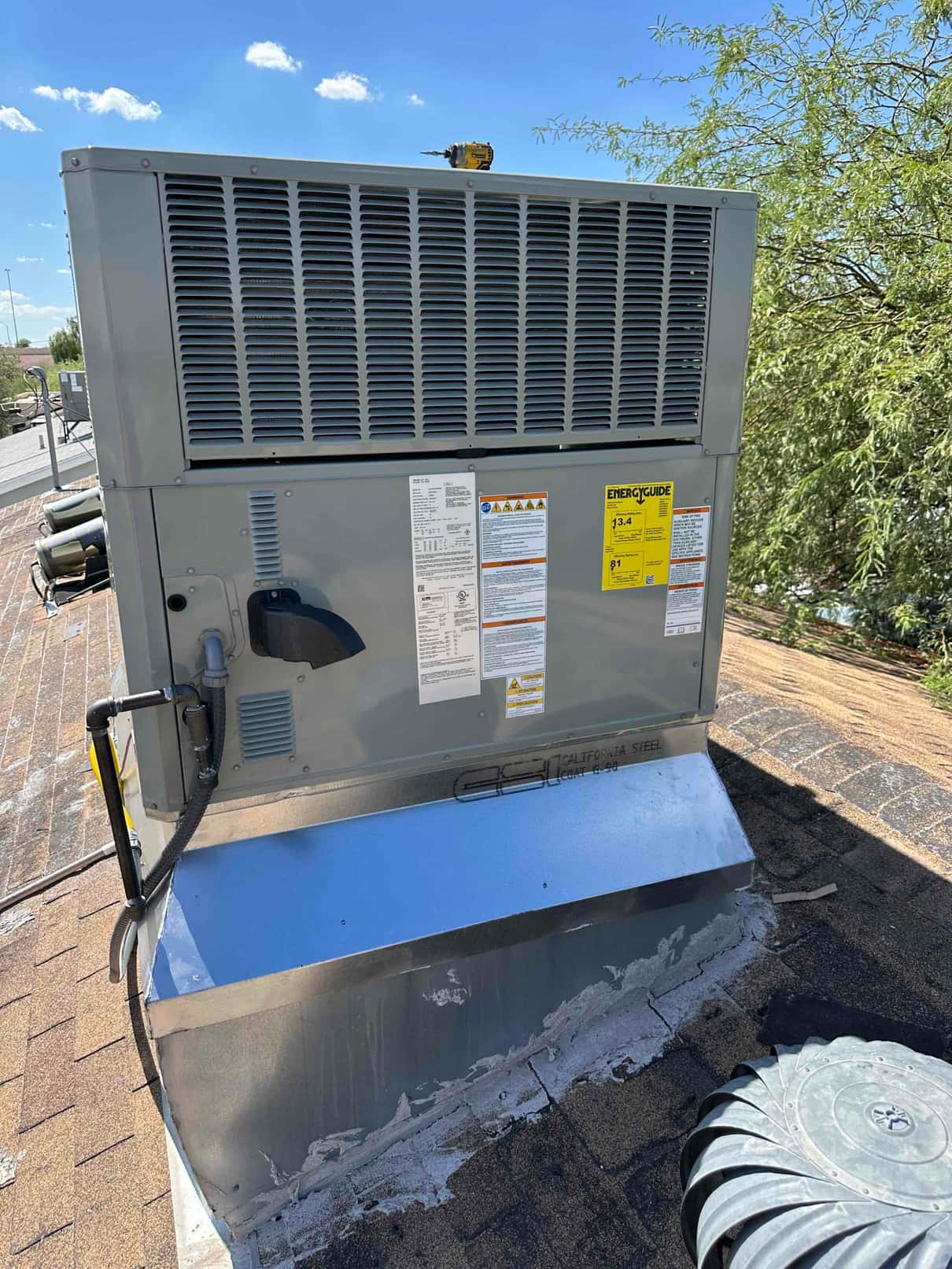 New rooftop package HVAC unit installed on a curb with sealed flashing and electrical whip connected on the side.
