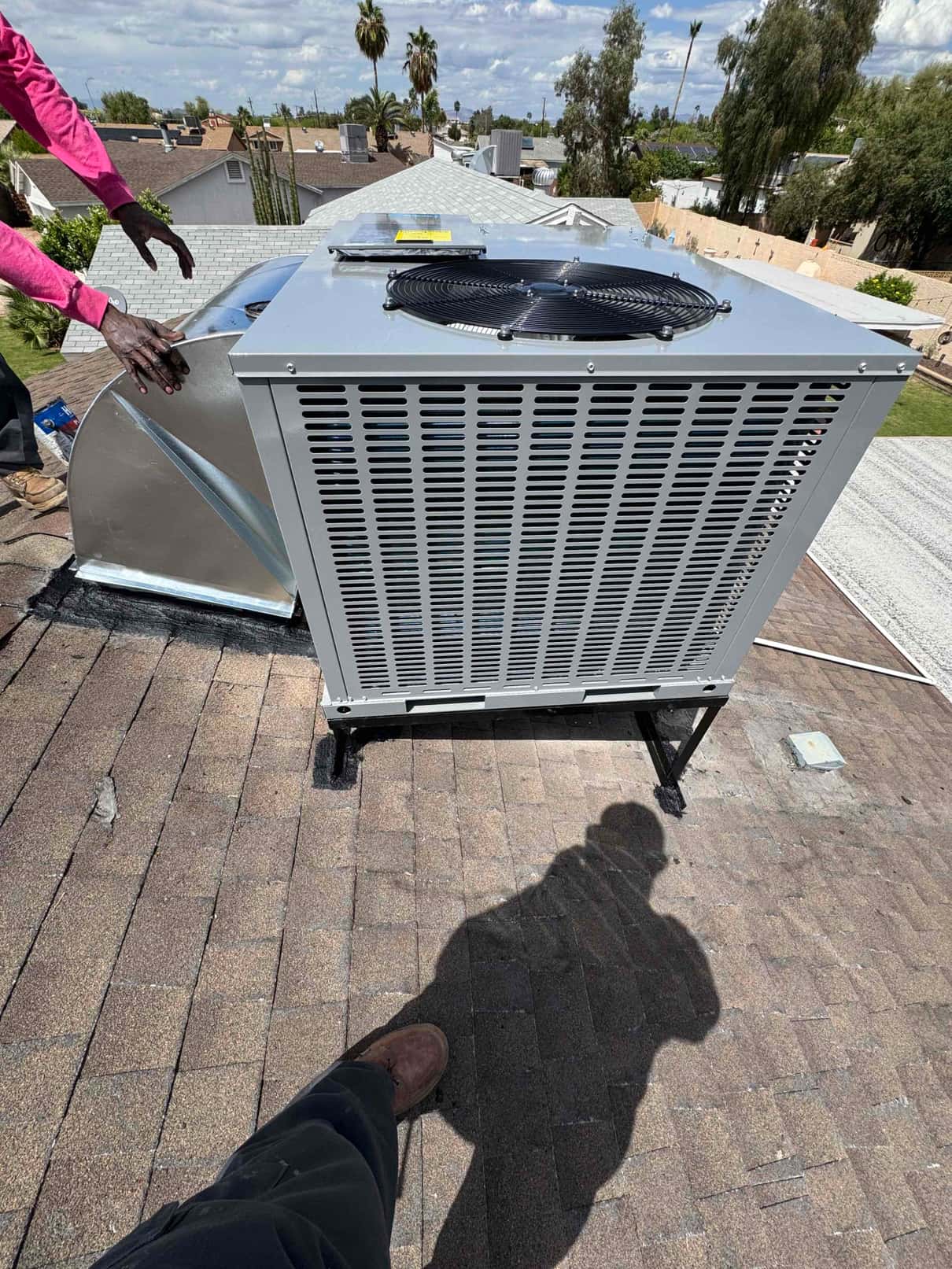 New rooftop package unit set on a raised stand, aligned to the curb adapter and roof penetration, during installation.