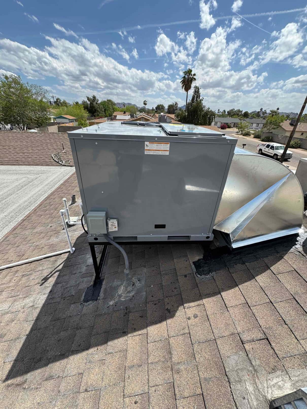 New rooftop package unit set on stand with sealed roof penetrations, electrical disconnect, and sheet metal duct transition connected.