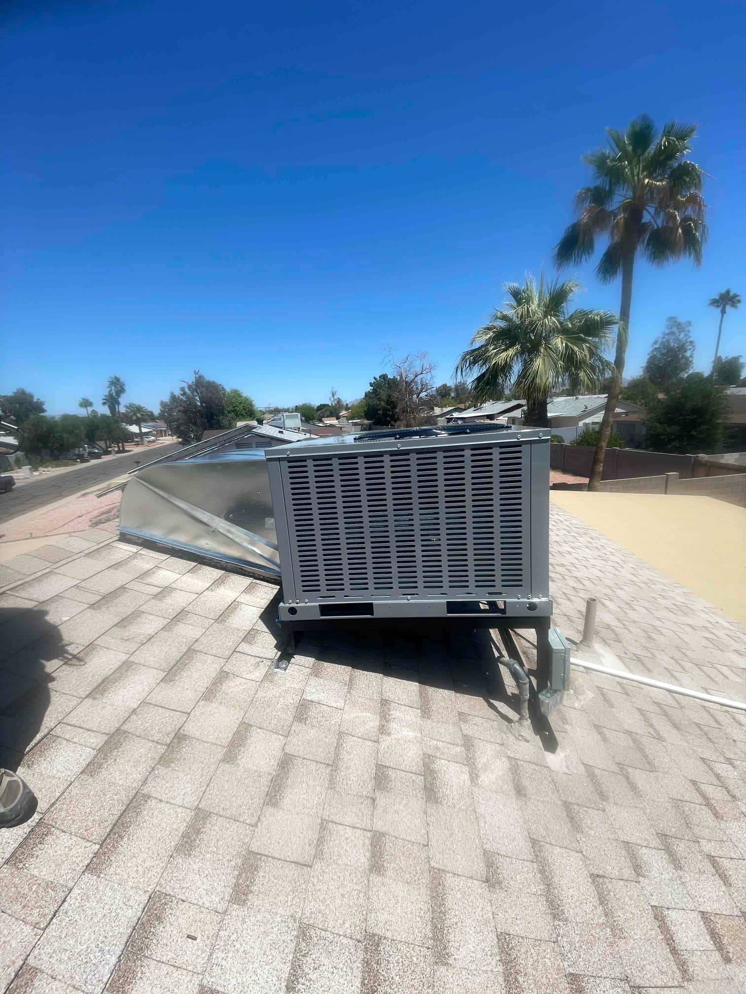 New rooftop package unit set on stands with sealed roof curb and connected condensate drain and electrical whip.