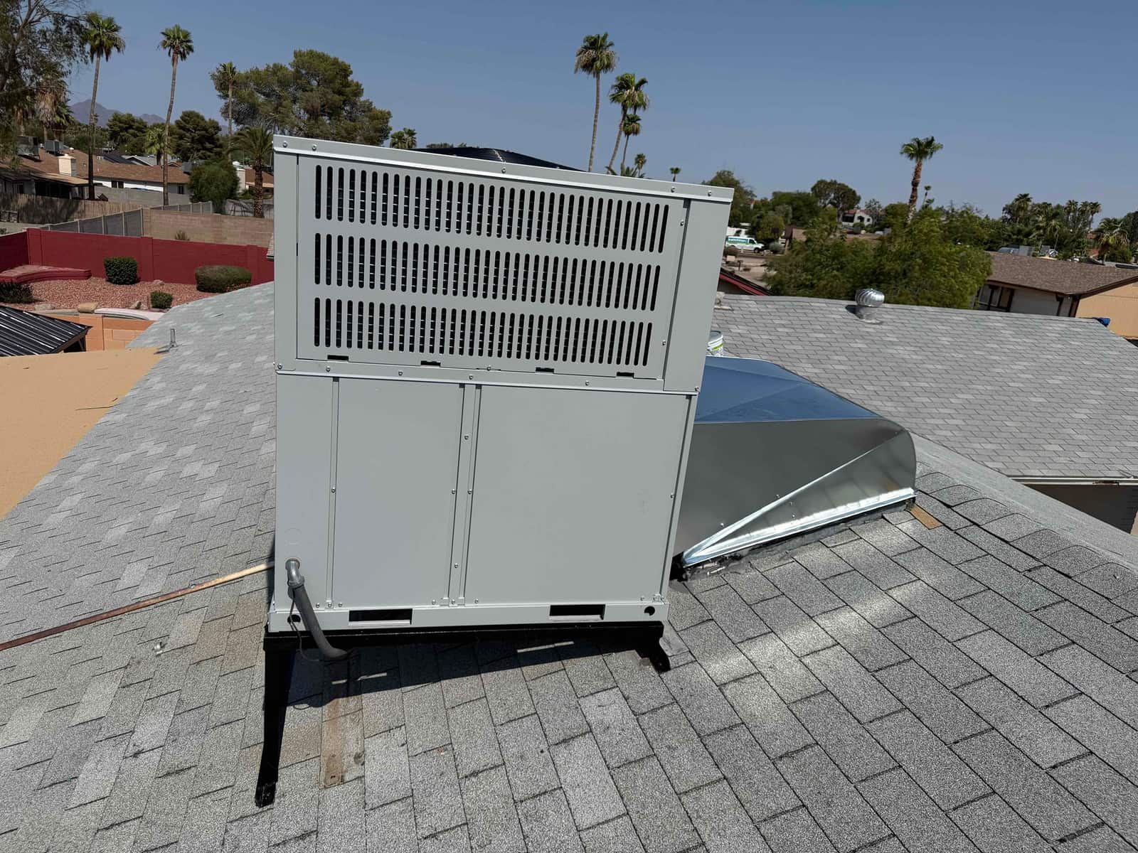 New rooftop packaged HVAC unit set on steel stands with connected duct curb and sealed roof penetration.