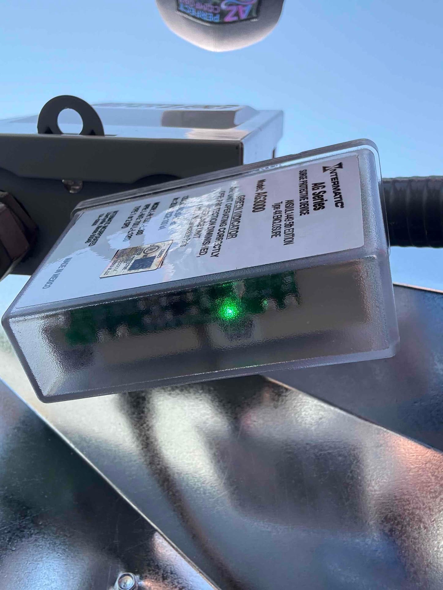 Outdoor disconnect with an installed protective device showing a green status indicator LED during HVAC installation.