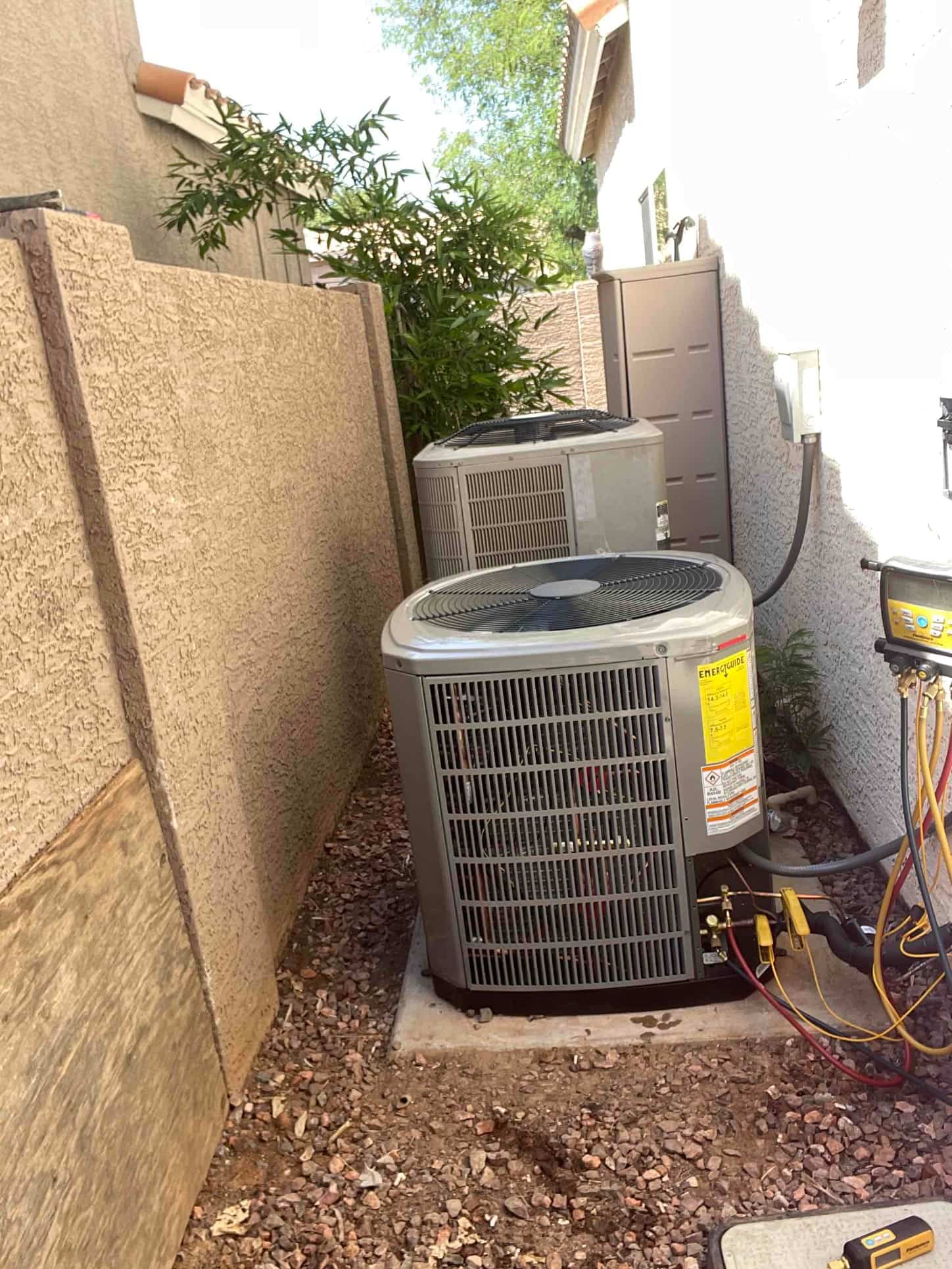 Two outdoor heat pump condensers set on level pads with insulated line sets and service valves accessible in the side yard.