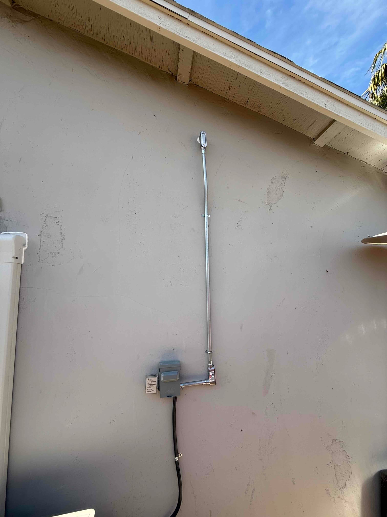 Outdoor HVAC disconnect with rigid conduit neatly routed up the wall to a weatherproof service head, completed and secured.
