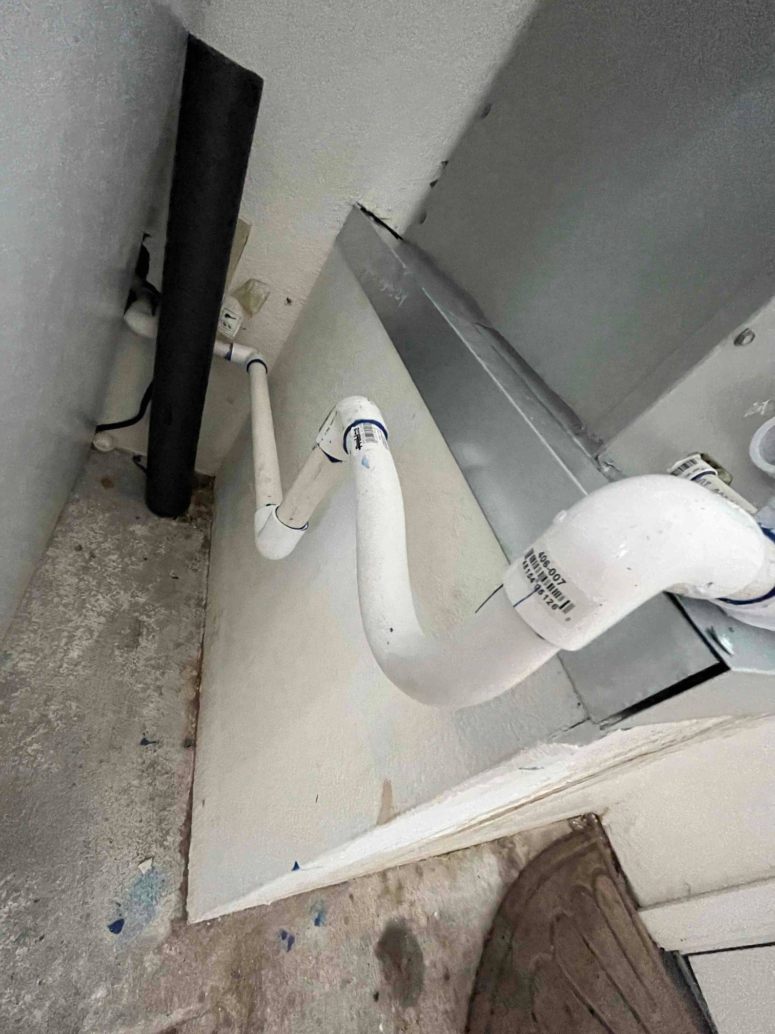 PVC condensate drain with cleanout and trap connected to the air handler, showing routed piping and insulated suction line nearby.
