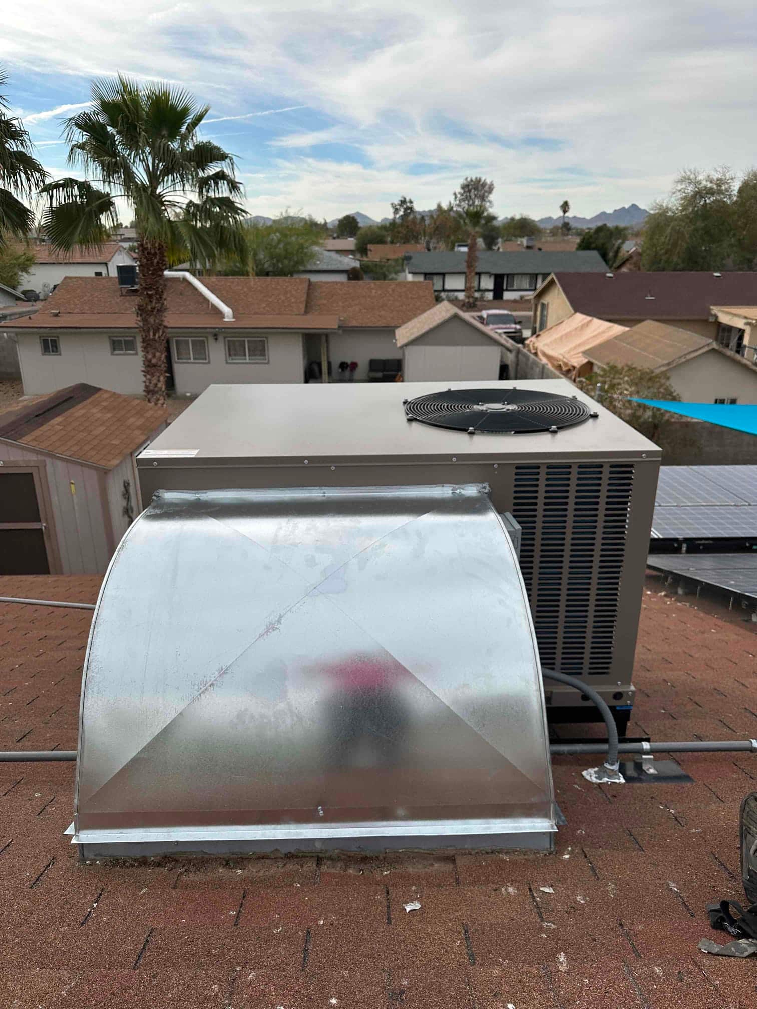 Rooftop package HVAC unit installed with new galvanized curb adapter and sealed electrical conduit on a shingle roof.