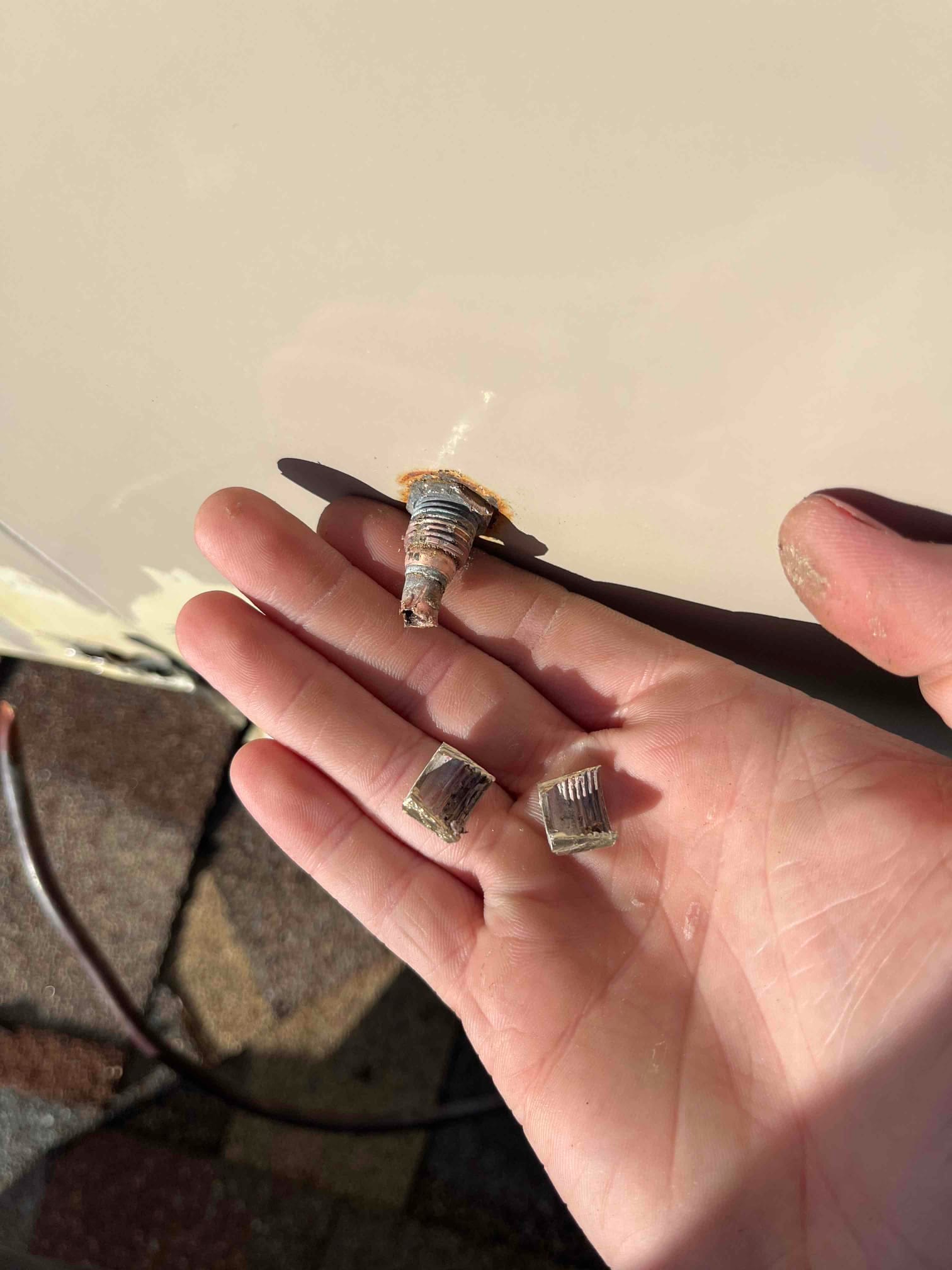 Technician’s hand holds a corroded float valve component and two broken metallic fragments removed from HVAC equipment.
