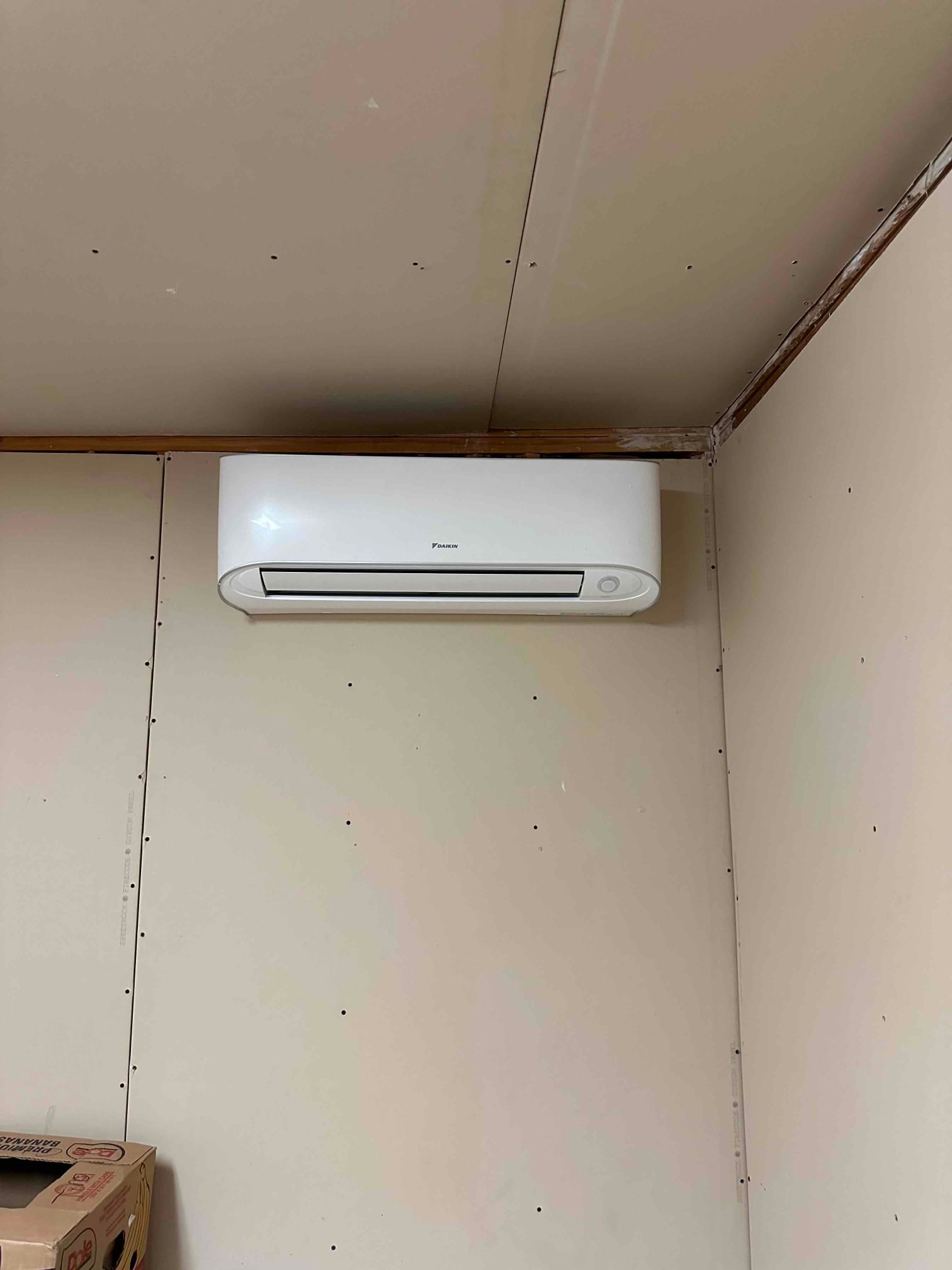 Wall-mounted mini-split indoor unit installed on finished drywall, positioned near the ceiling for optimal air distribution.