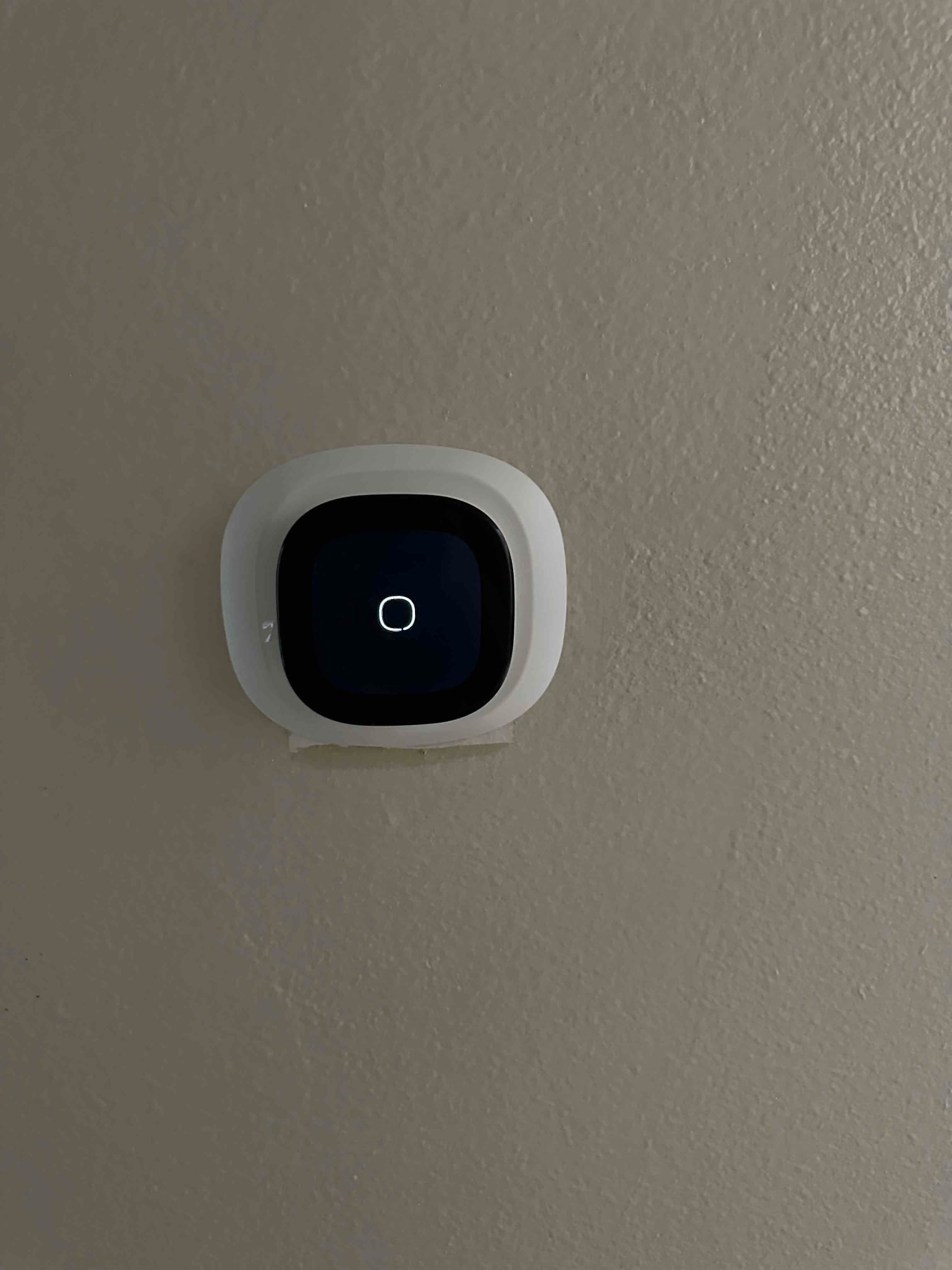 Wall-mounted smart thermostat installed and powered on, completing controls setup for the new HVAC system.