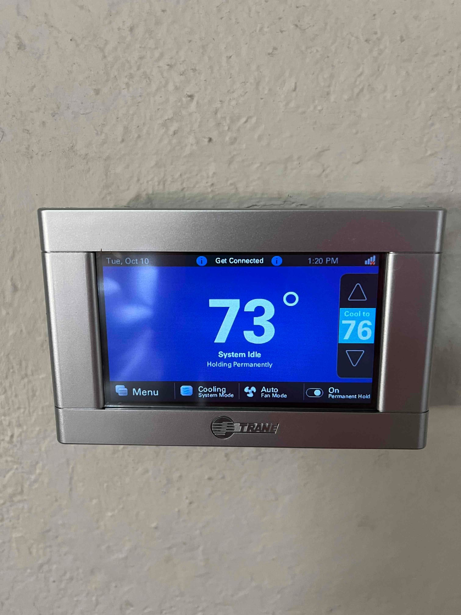 Wall-mounted touchscreen thermostat displays indoor temperature of 73 degrees with system idle and cooling mode selected.