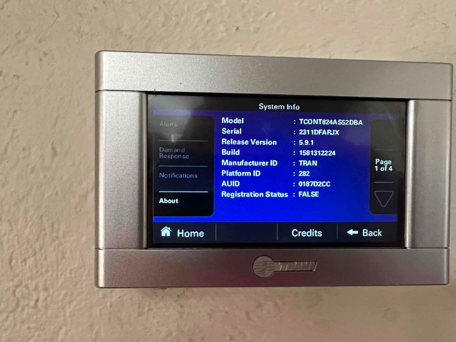 Wall-mounted touchscreen thermostat displays system information menu during setup after installation.