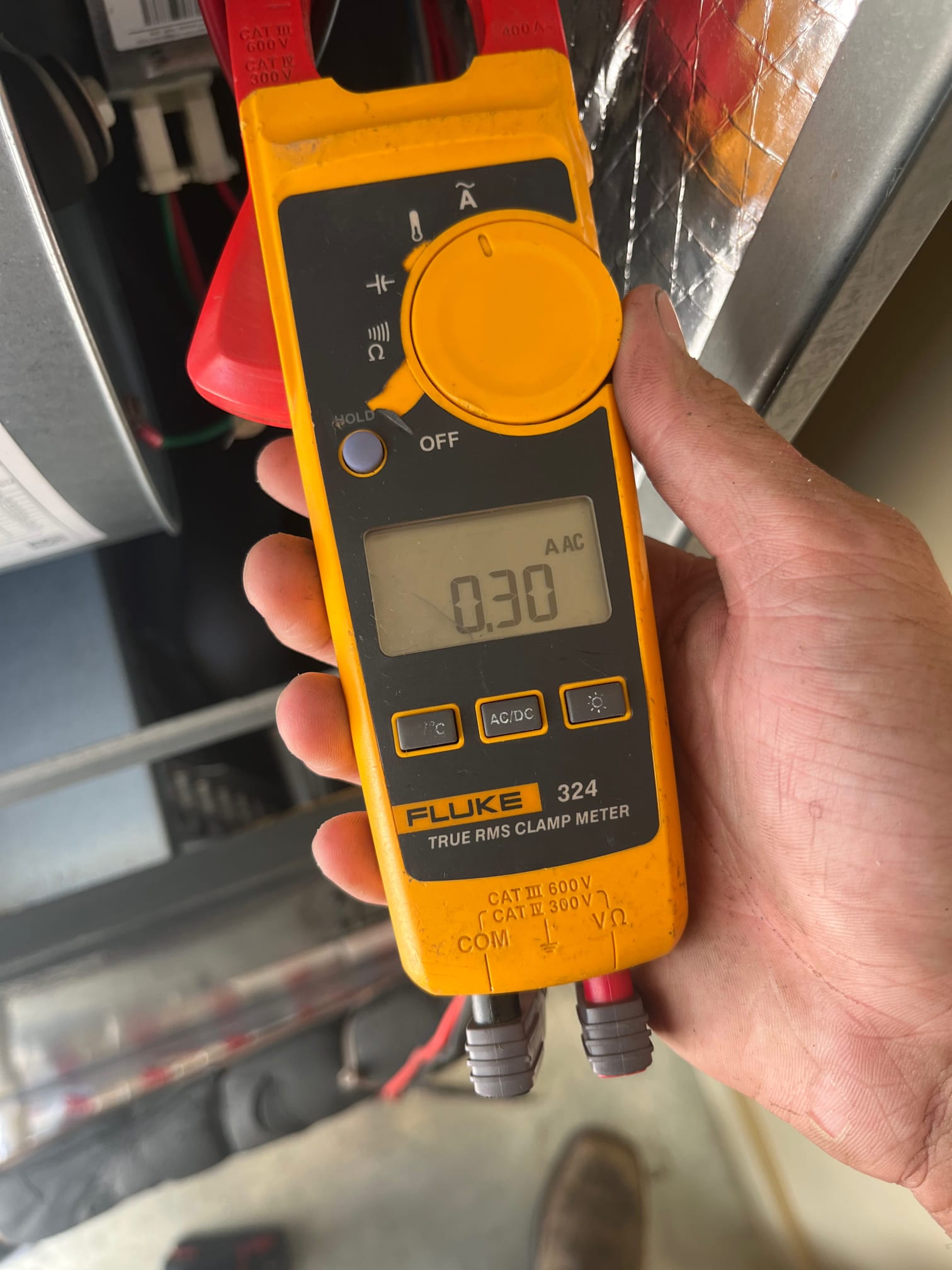 Clamp meter displays 0.30 A AC while measuring current on a conductor inside the air handler compartment.