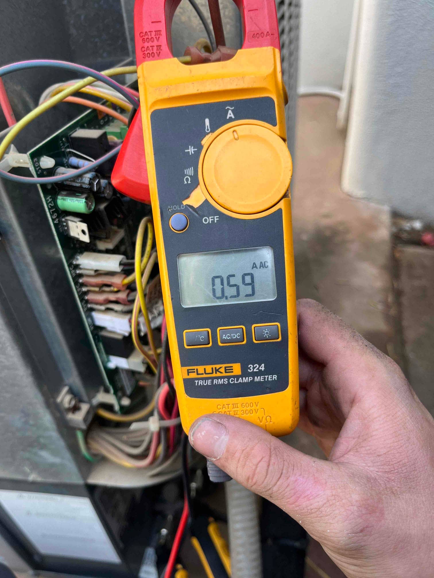 Clamp meter displays 0.59 A AC while clamped on a single conductor inside the air handler control compartment.
