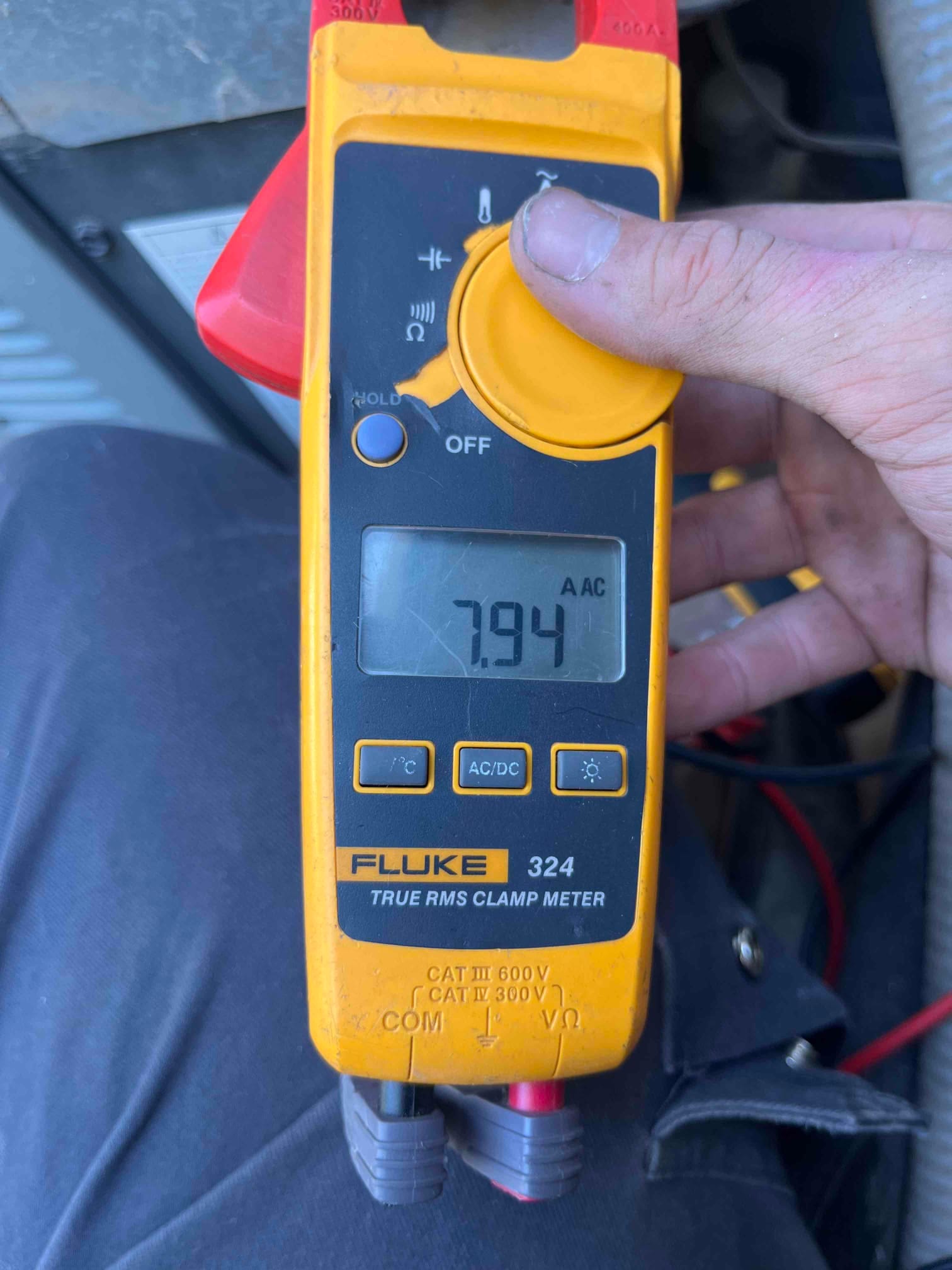 Clamp meter displays 7.94 A AC while measuring current on a clamped conductor at the air conditioning repair site.