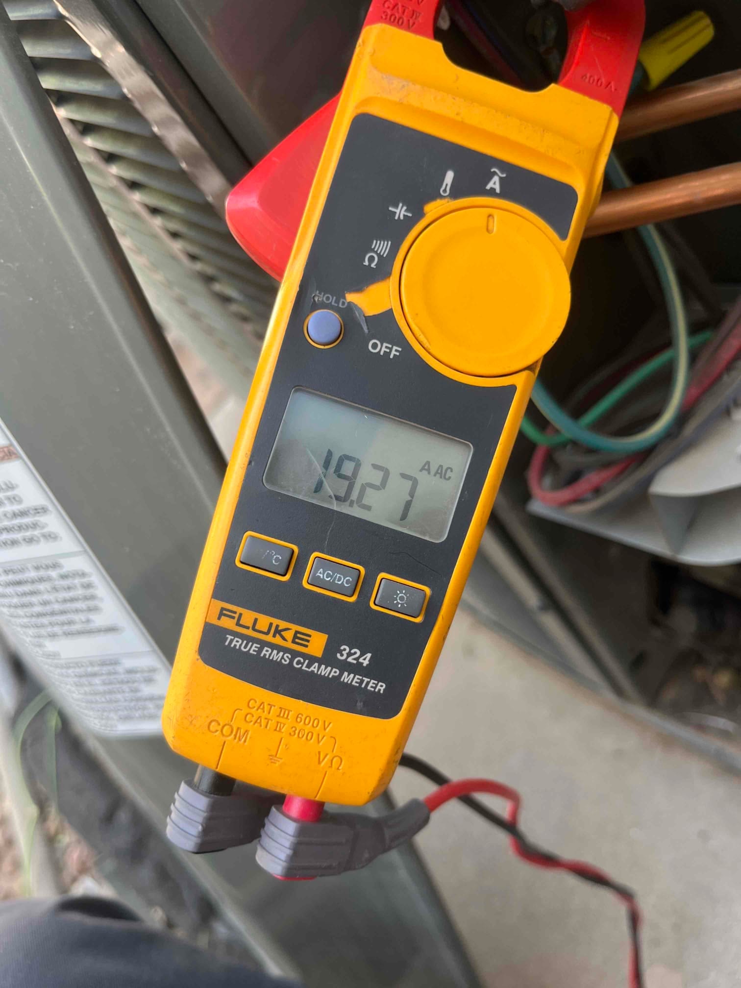 Clamp meter shows 19.27 A AC on the clamped conductor at the air conditioning unit.