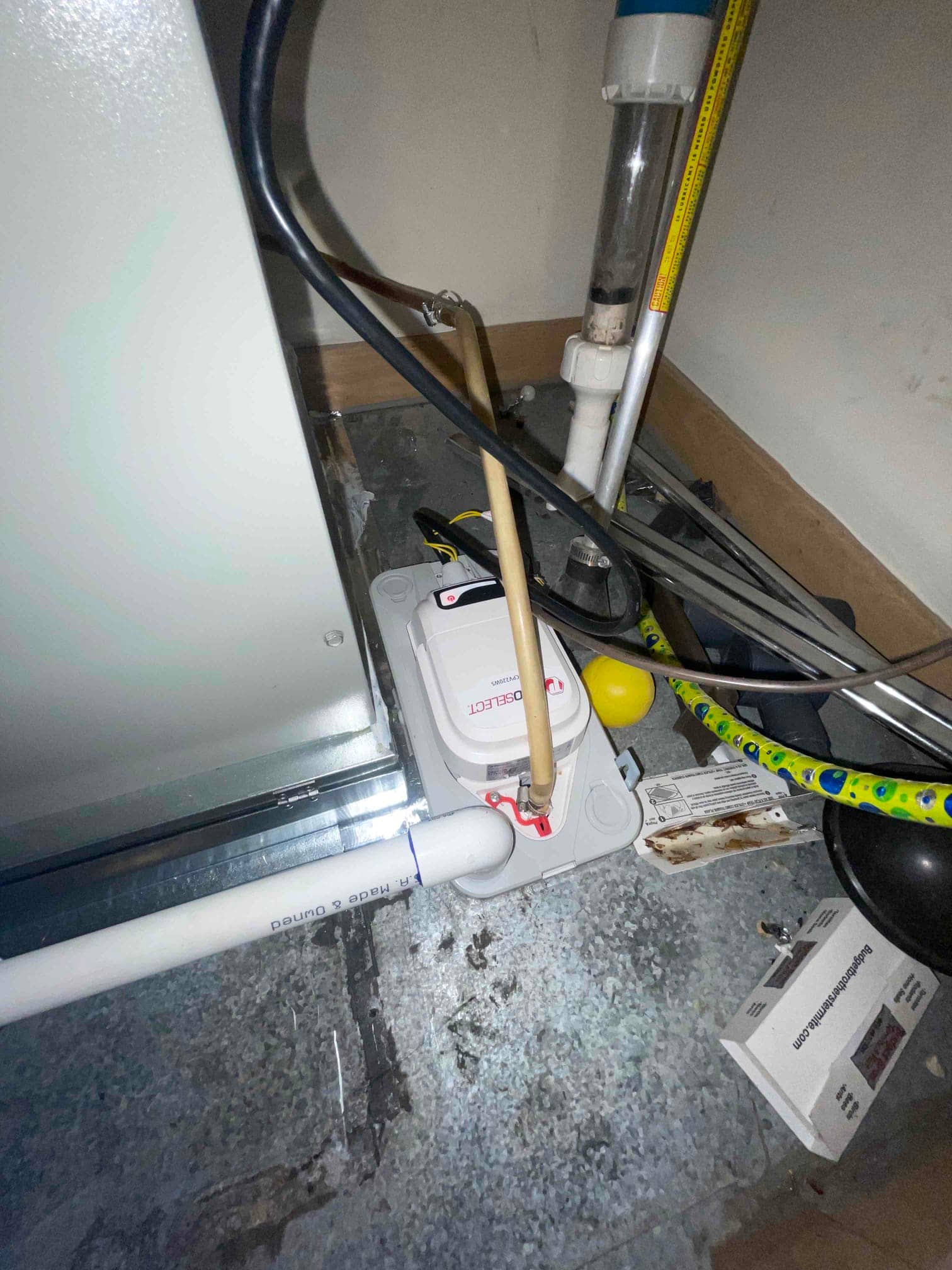 Condensate pump connected to the air handler drain line, with PVC piping and flexible tubing routed to manage condensate removal.
