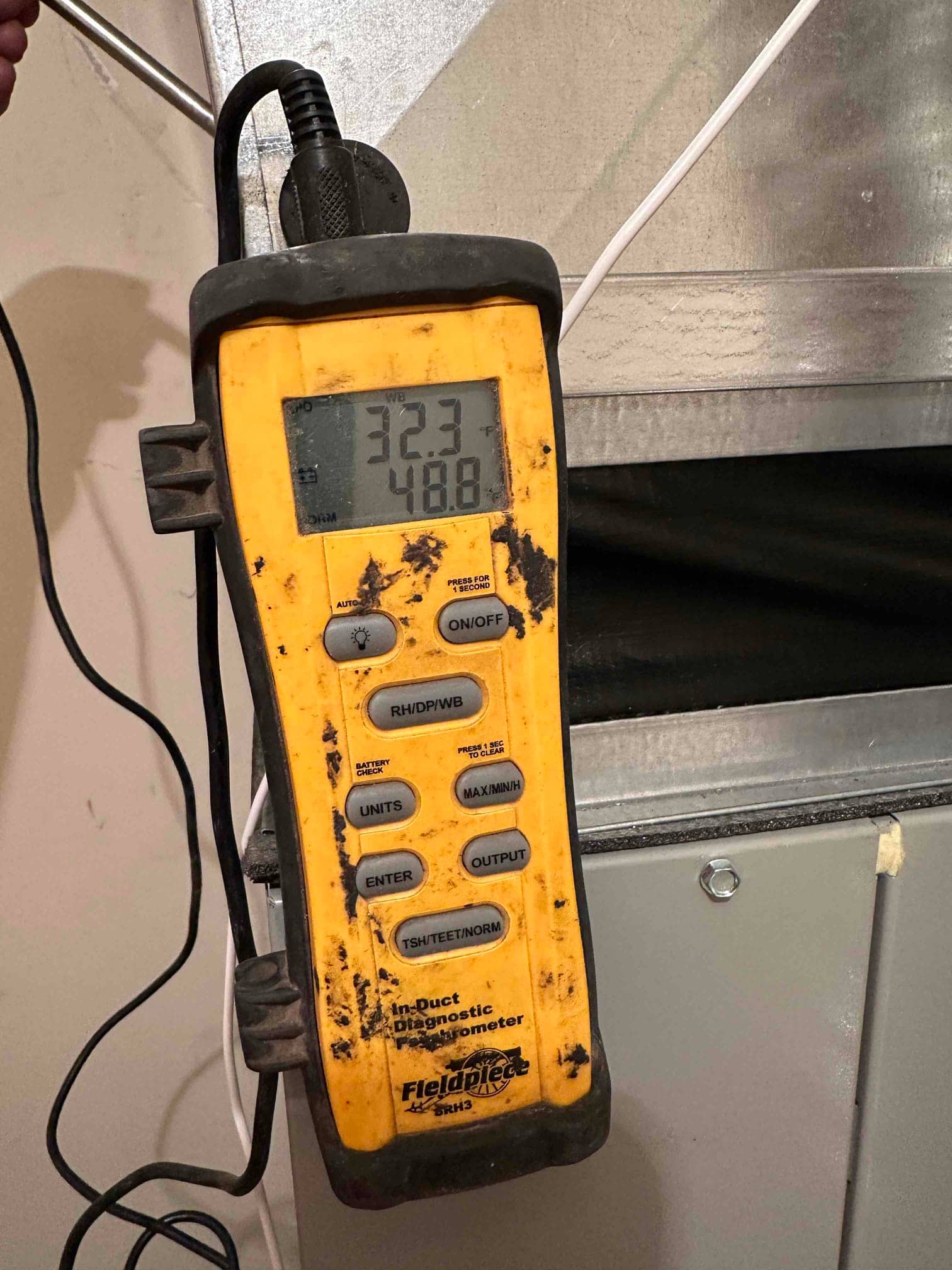 Digital in-duct thermometer displays 48.8°F while measuring supply air temperature at the plenum of the installed system.