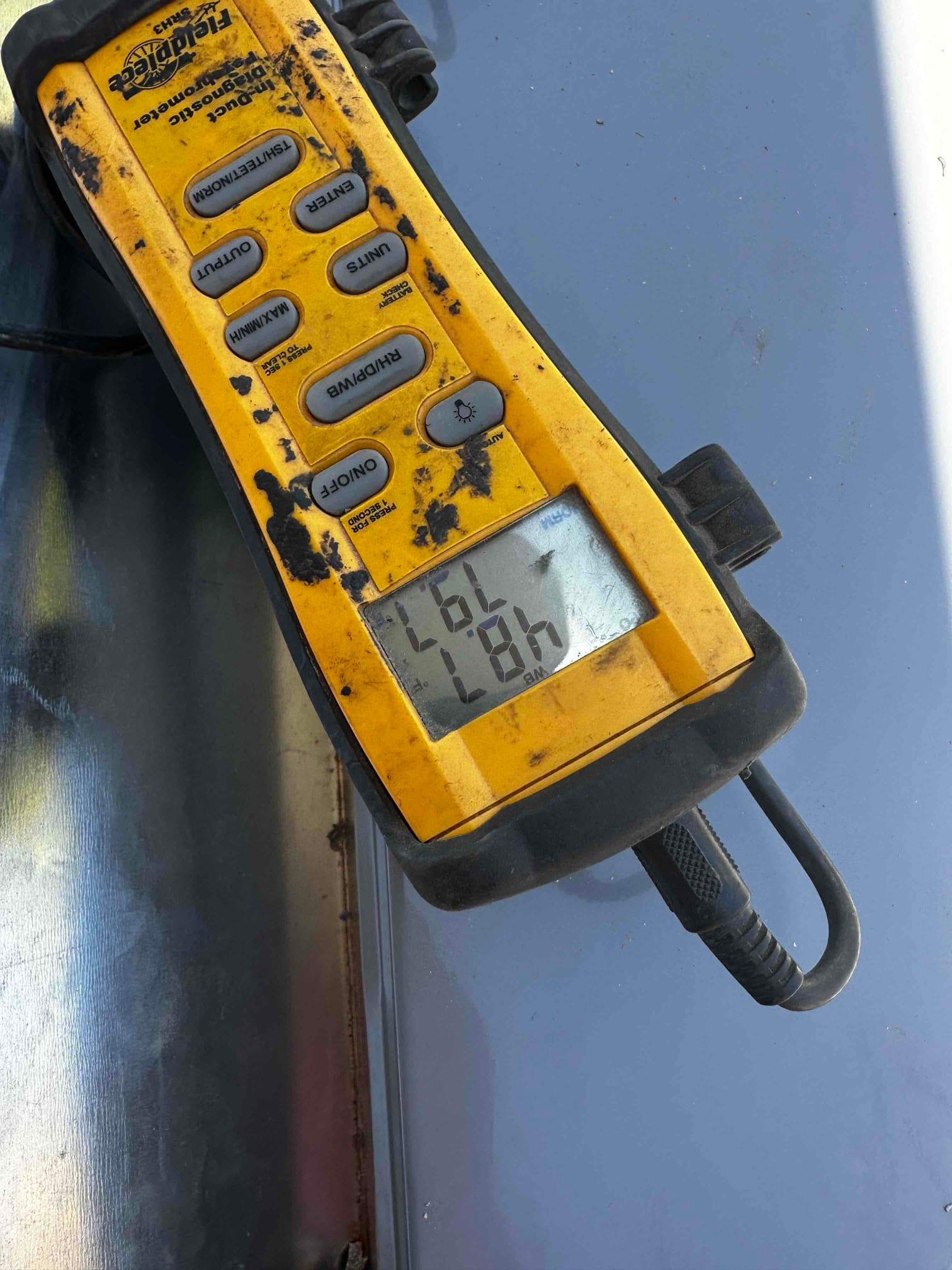 Digital duct thermometer displays 57.8°F during air balance checks on the newly installed HVAC system.