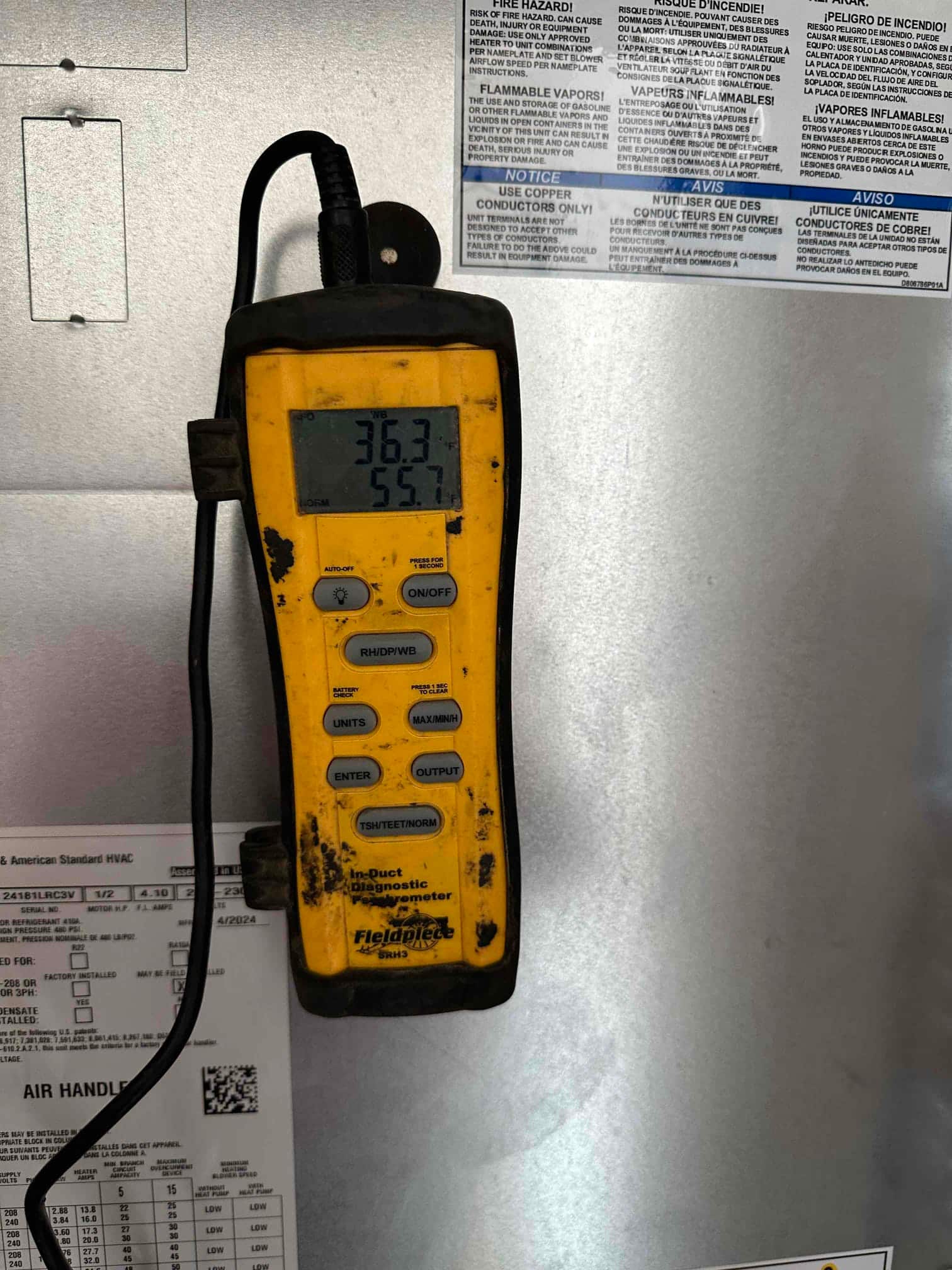 Digital HVAC meter on the air handler shows a temperature reading of 55.7°F during air-side commissioning.