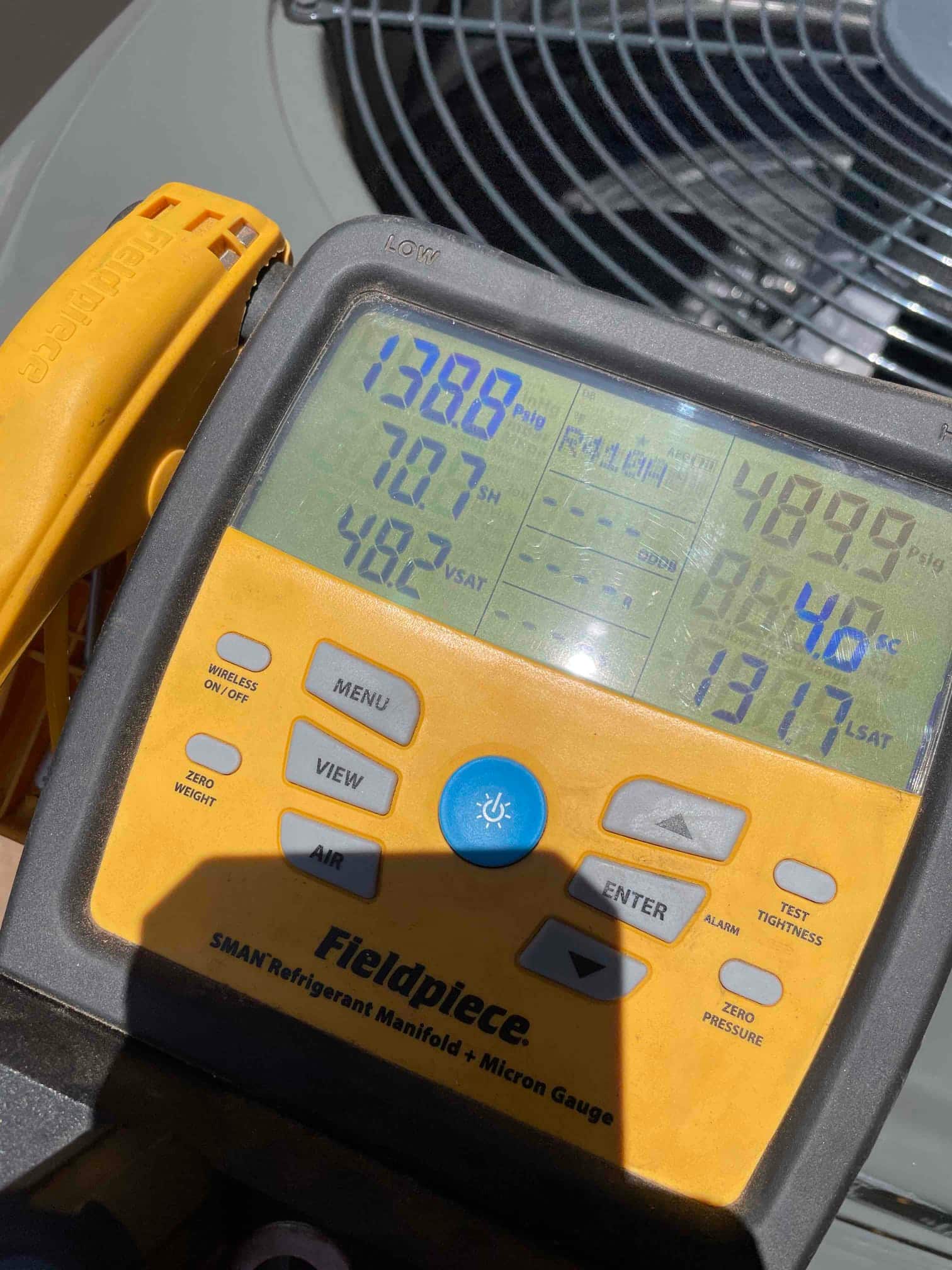 Digital manifold connected at the outdoor unit shows operating suction and liquid pressures during system commissioning.
