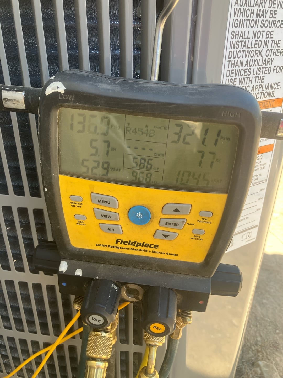 Digital manifold shows operating pressures with R-454B selected during system commissioning at the outdoor condenser.
