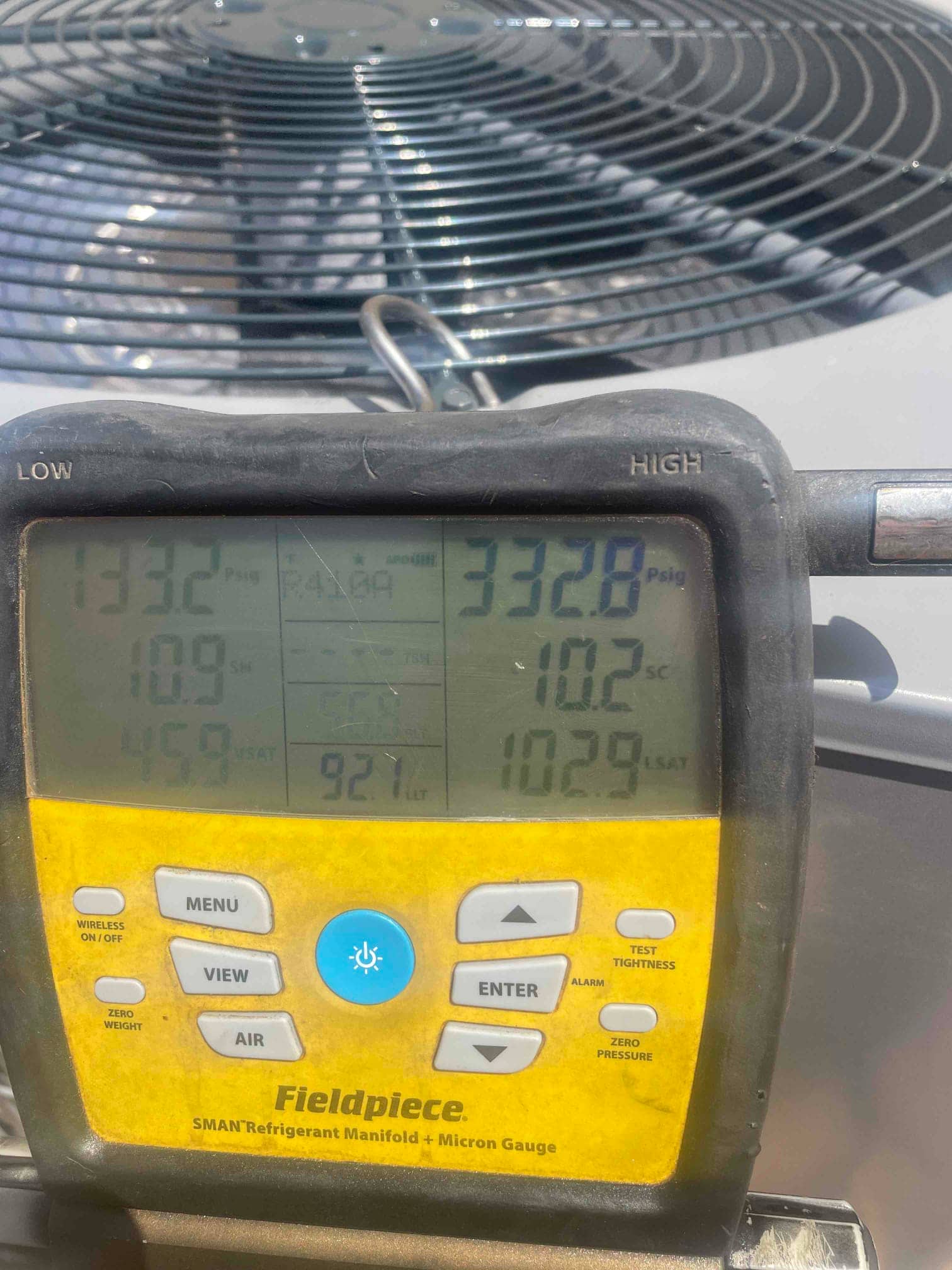 Digital manifold shows system operating pressures with split readings during commissioning at the outdoor condenser.