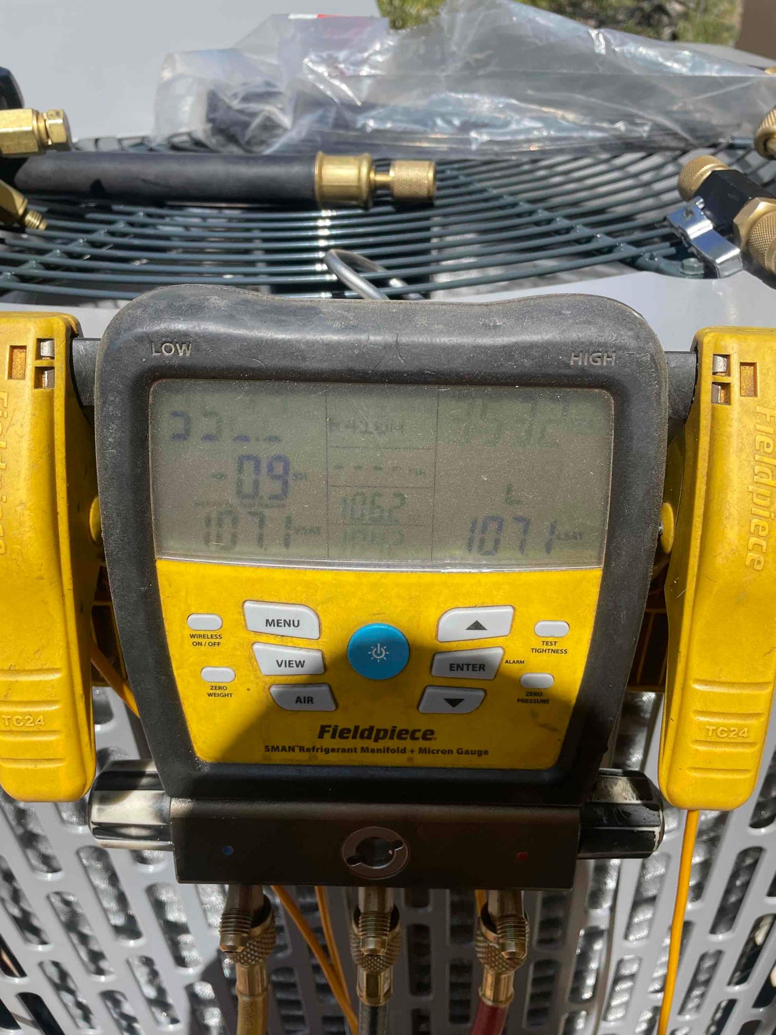 Digital micron gauge on the outdoor unit shows a deep vacuum achieved during system evacuation prior to refrigerant charging.