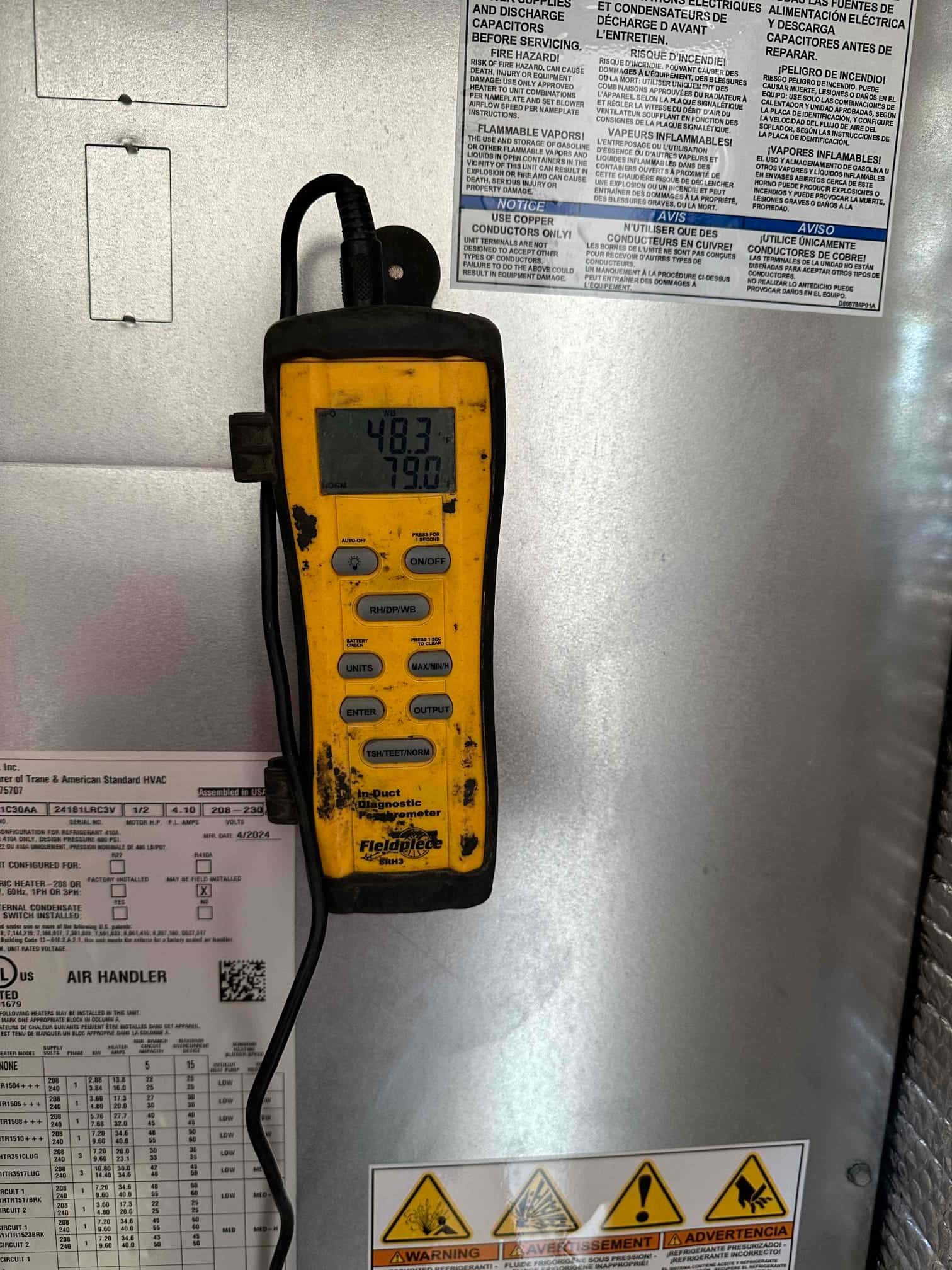 Digital thermometer attached to the air handler shows 48.3°F supply air and 79.0°F return air during commissioning.